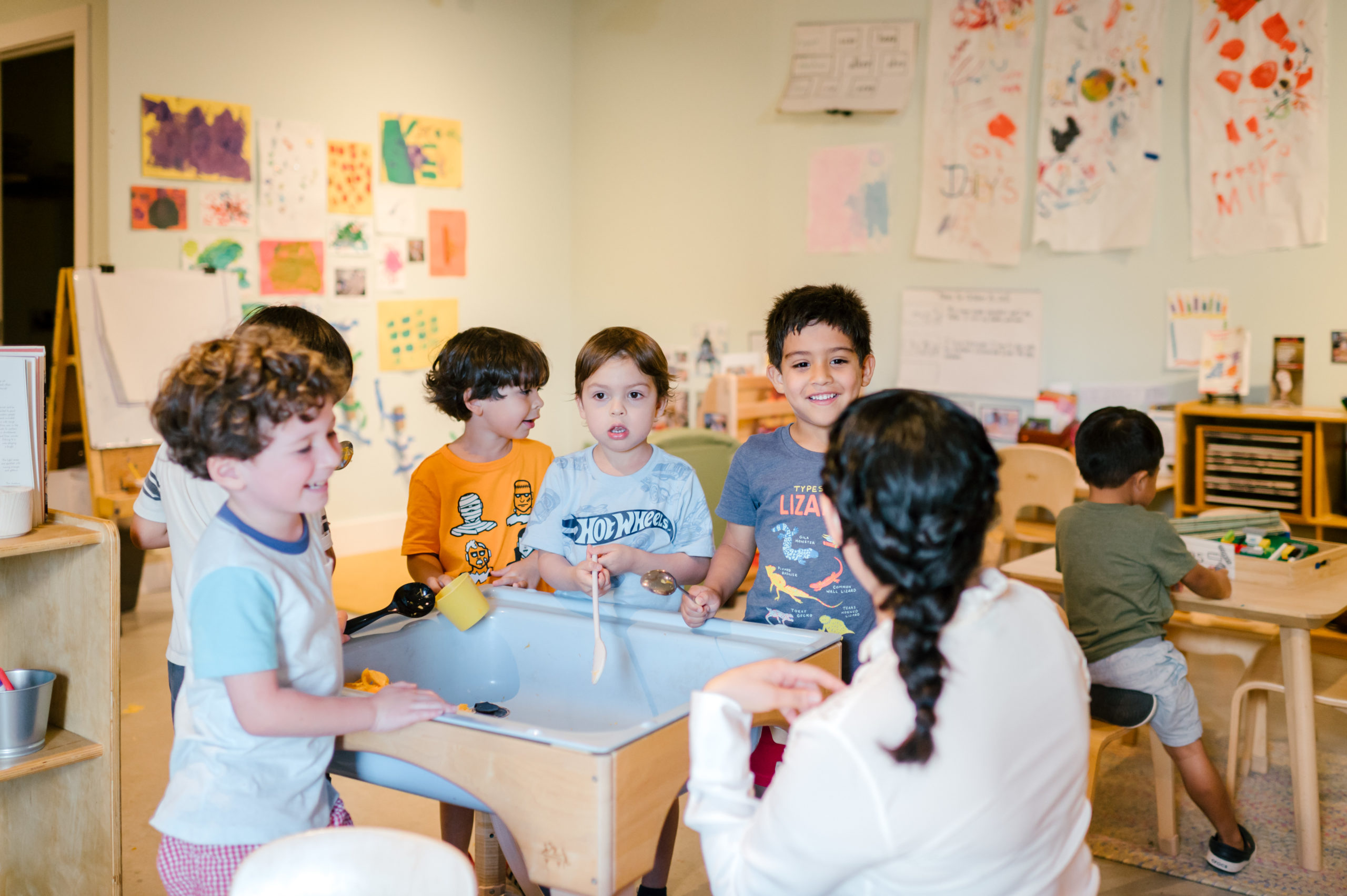 Photo of woman child development coach interacting with kids in a school classroom 
