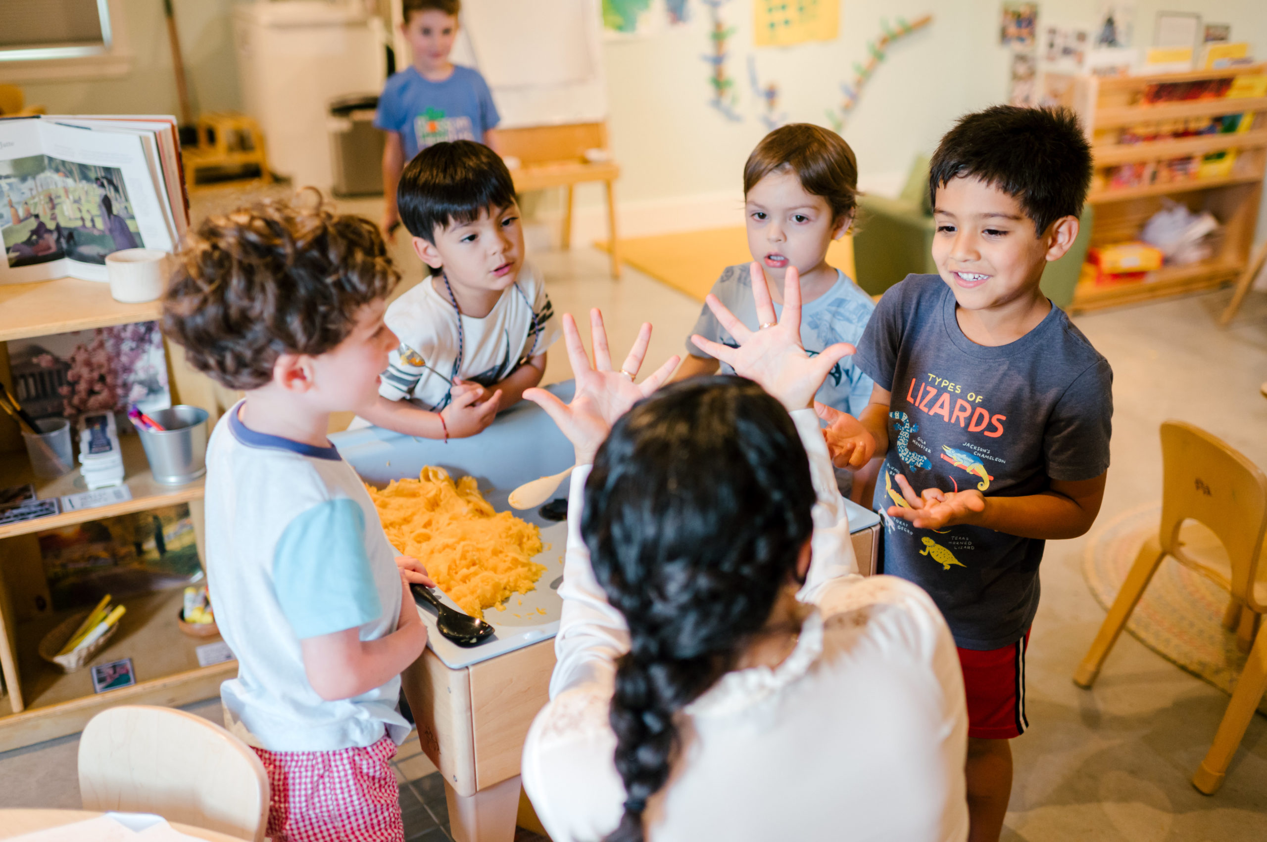 Photo of woman child development coach interacting with kids in a school room while they stare and interact with her back during her branding photography session