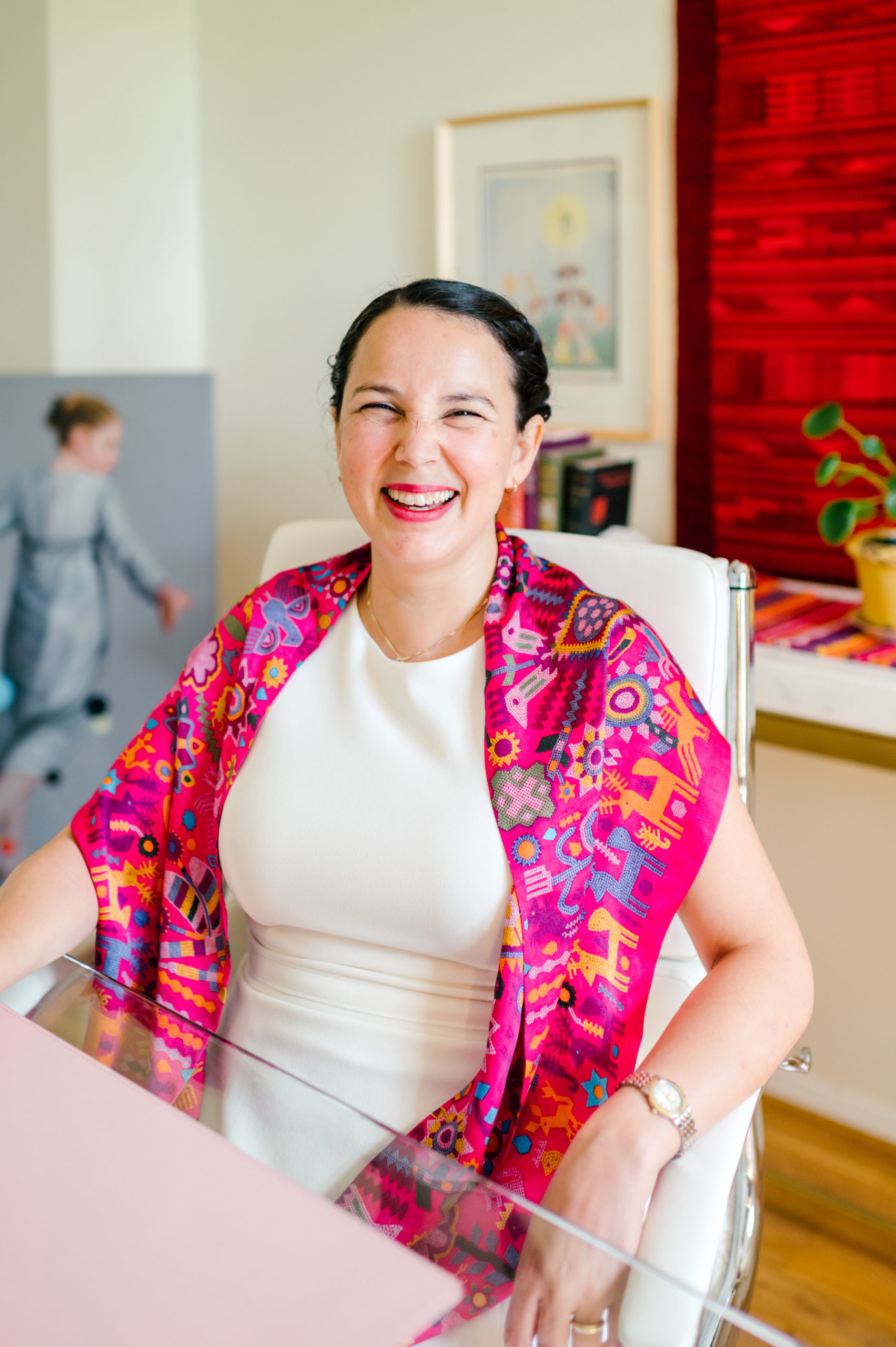 Photo of woman child development coach in a white dress and colorful pink scarf smiling 