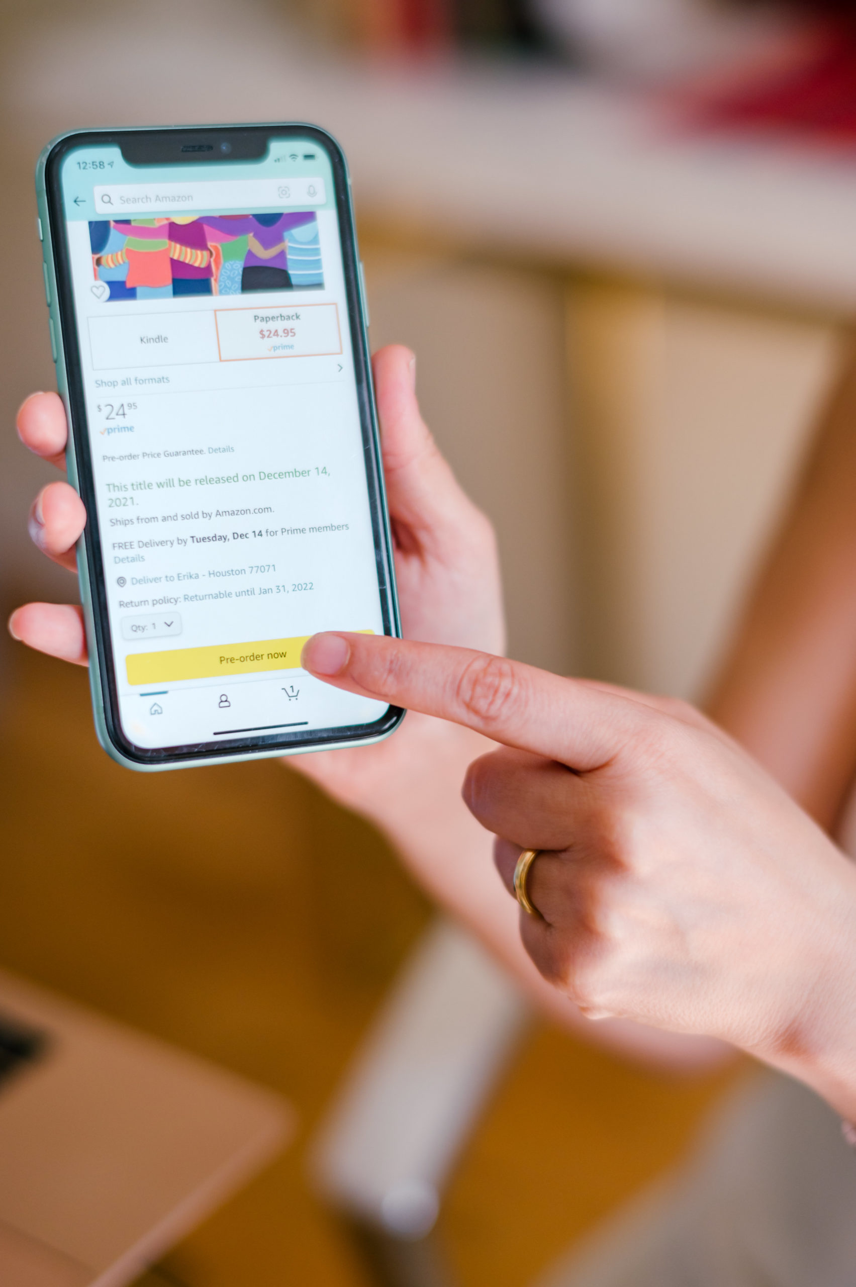 Photo of finger pointing to iPhone with a picture of the front cover of the book Hearing All Voices  during her branding photography session