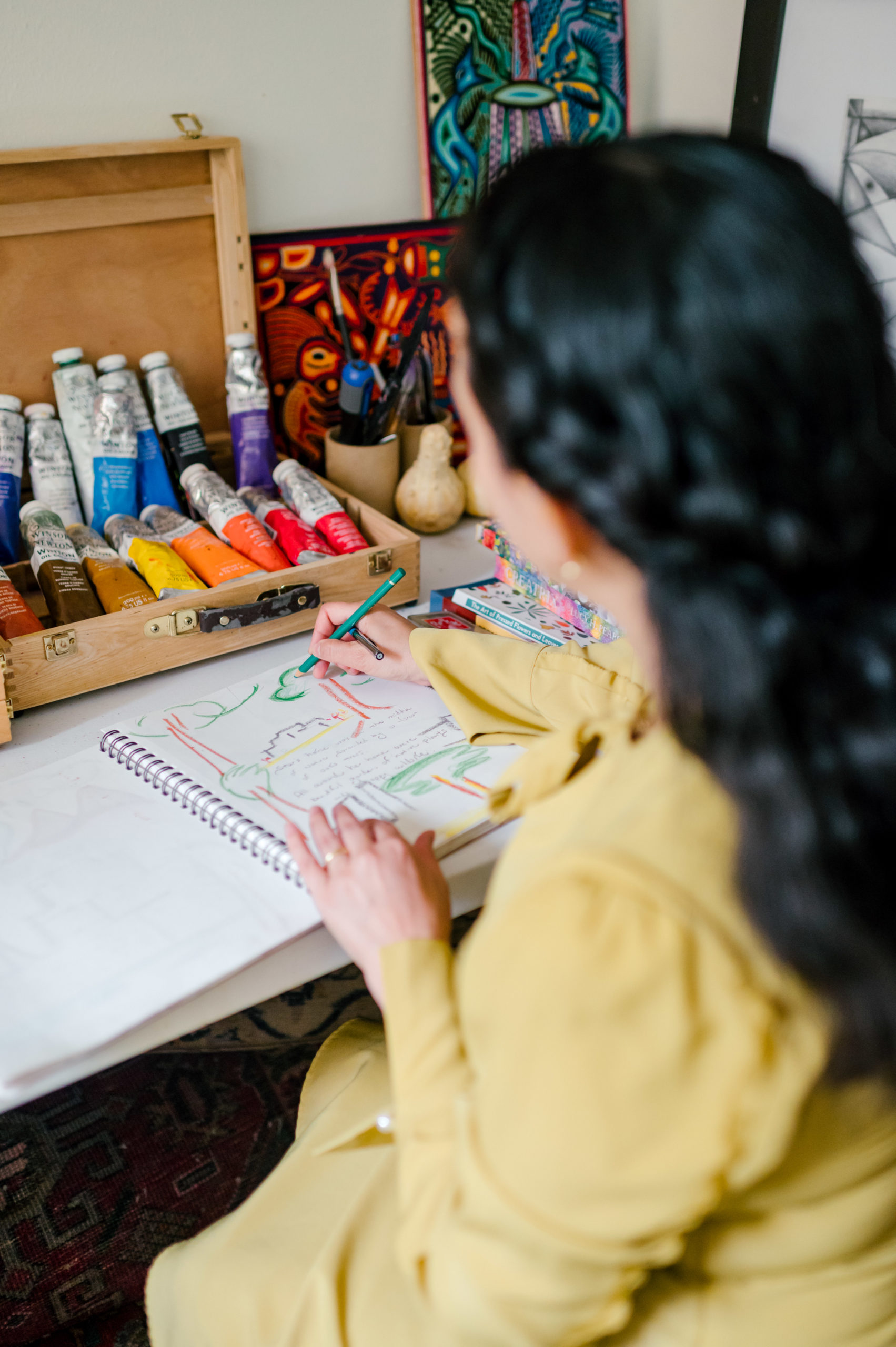 Photo of woman child development coach in her at home office drawing trees in her notebook  during her branding photography session