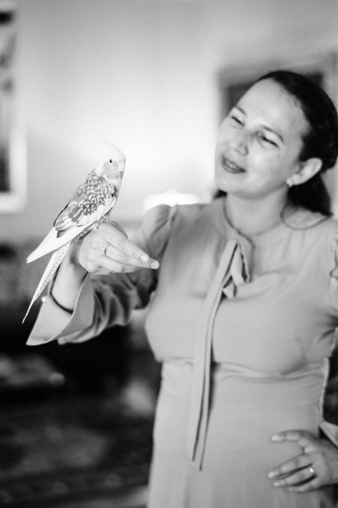 Black and White Photo of woman child development coach playing with her pet birds at home  during her branding photography session 