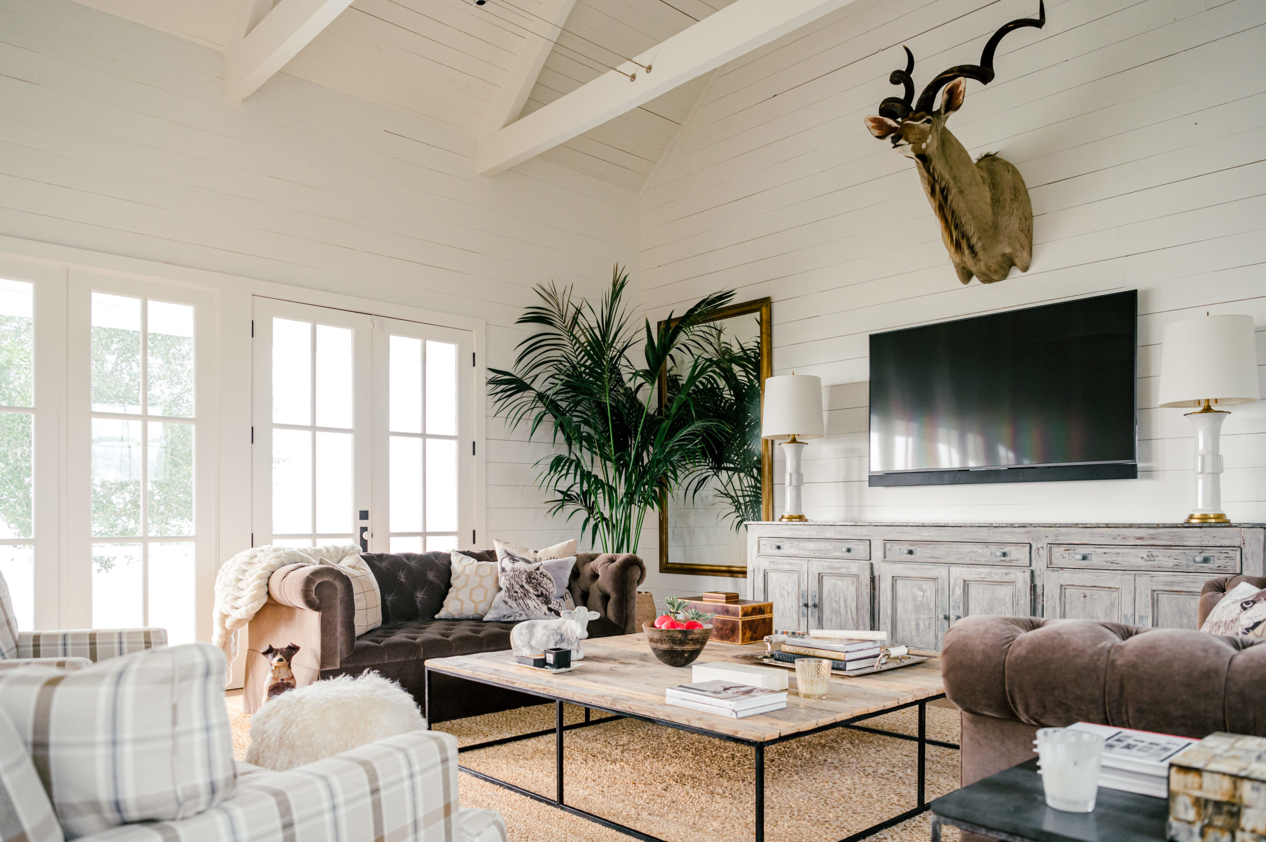 Interior Photography of living room furniture with a striped swivel chair and brown couches and a television hanging above a gray wooden dresser