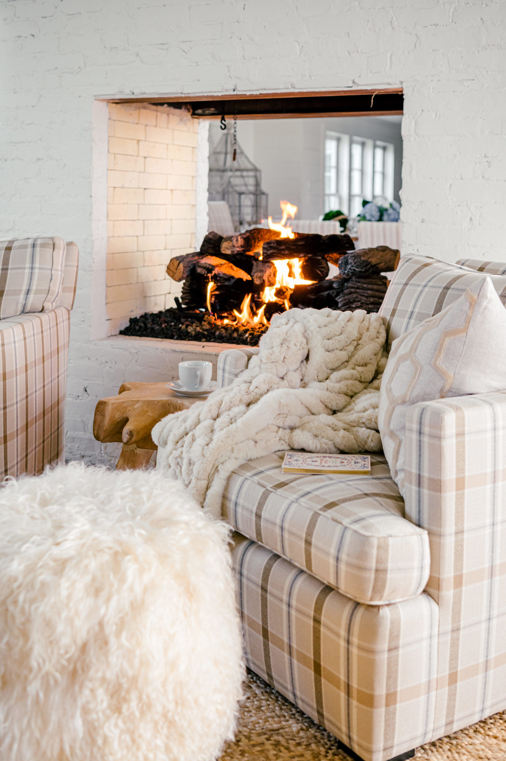 Striped tan love seat sitting near open fireplace indoors by a Houston Interior Photographer