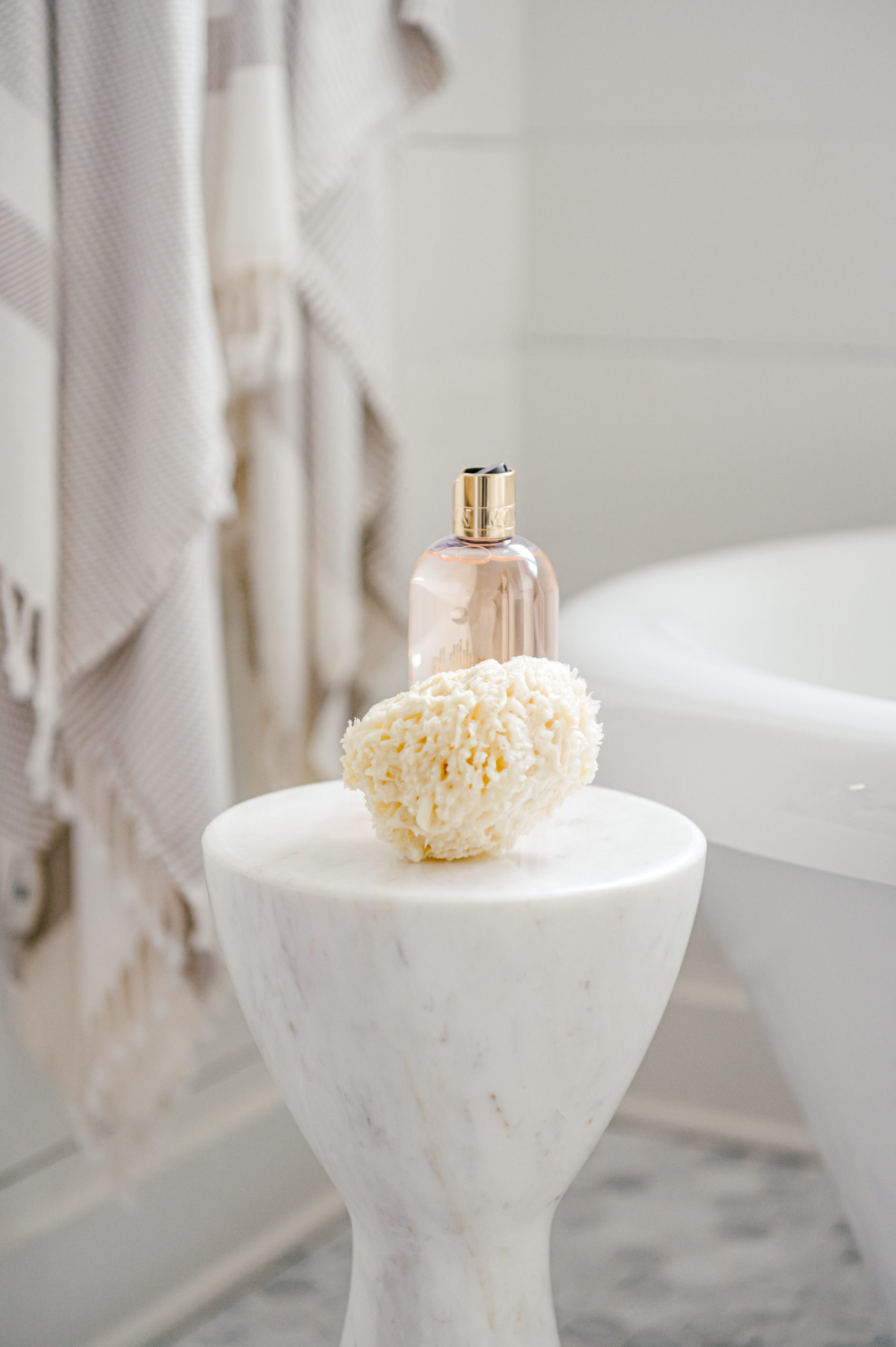 Interior Photography of pink soap bottle and calcite crystal on a white stone stool in the bathroom