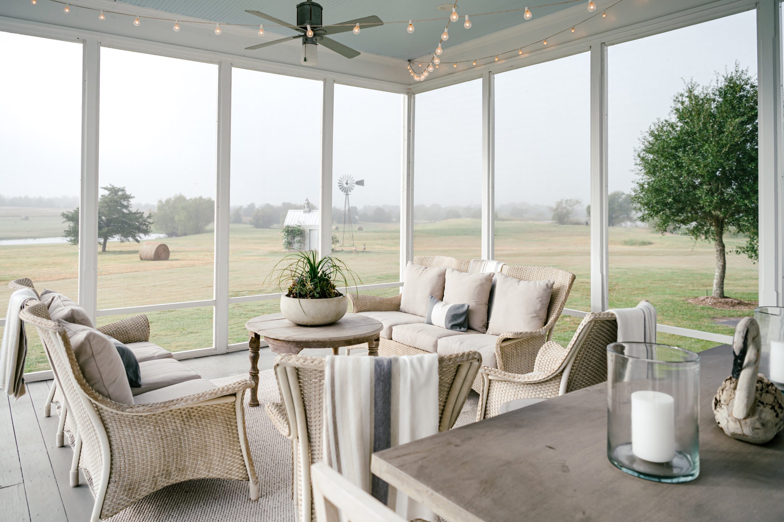 Photo of beautiful farmhouse porch furniture with two full walls of windows showcasing the beautiful farmland