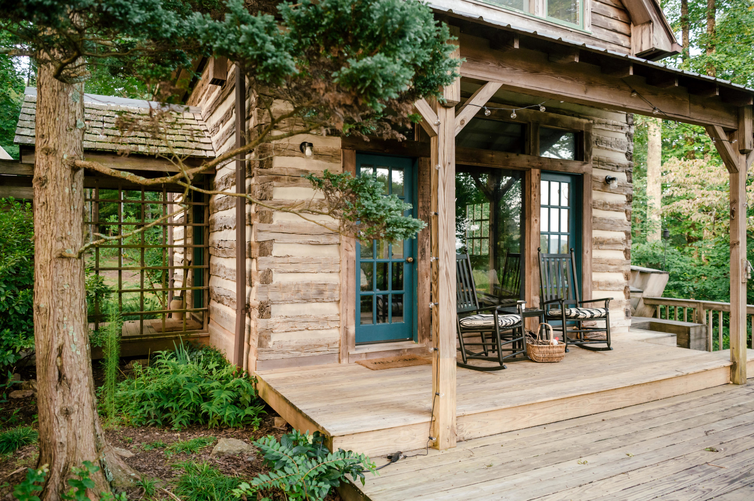 Professional air bnb photography of beautiful Cherry mountain cabin with greenery and chairs sitting on the front porch