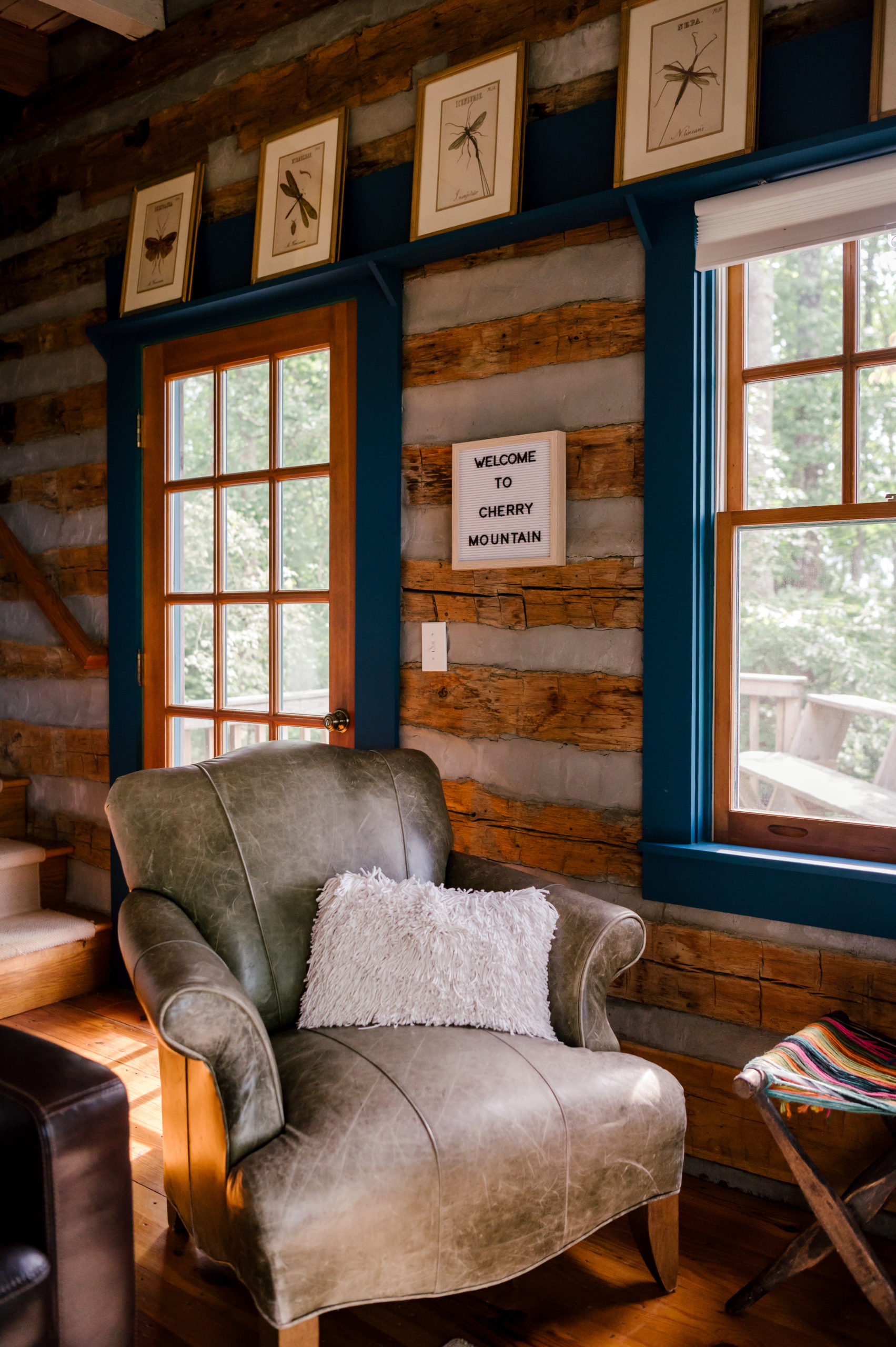 Professional Airbnb photography of grey leather loveseat in wooden cabin