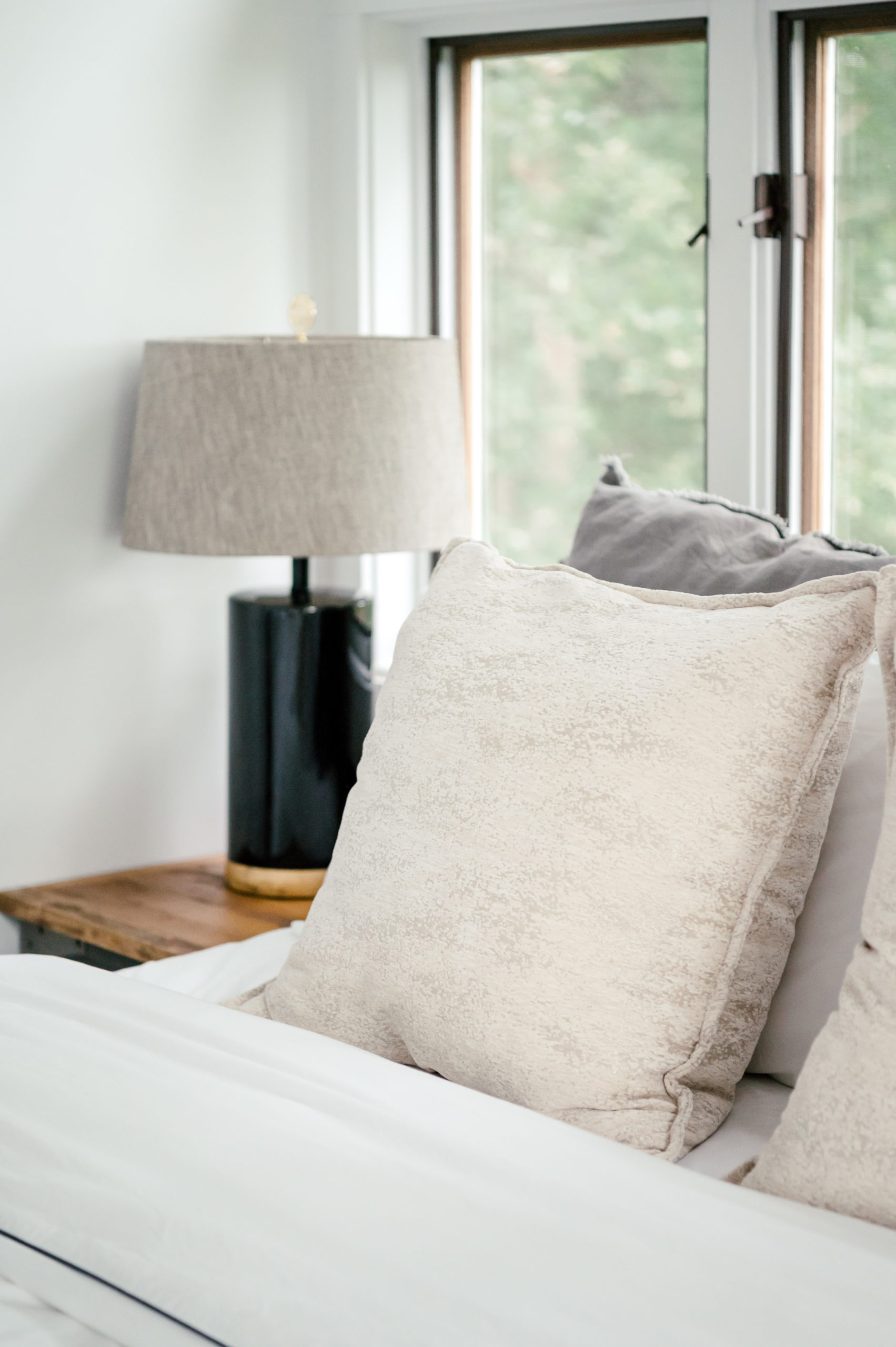 Photo of white pillows on bed in an air bnb bedroom and a lamp on the side table