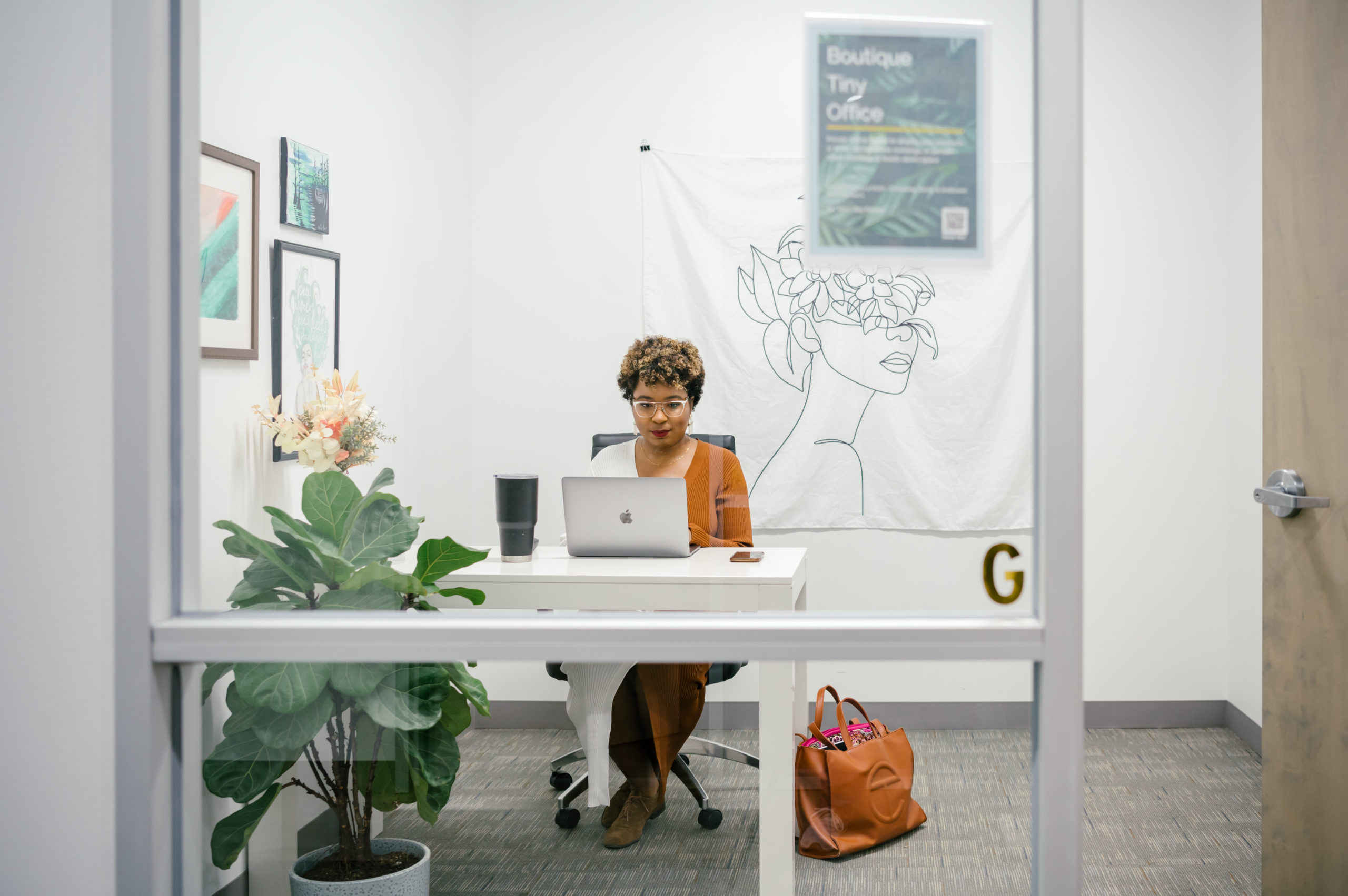 Photo of woman working in an enclosed office space on her computer