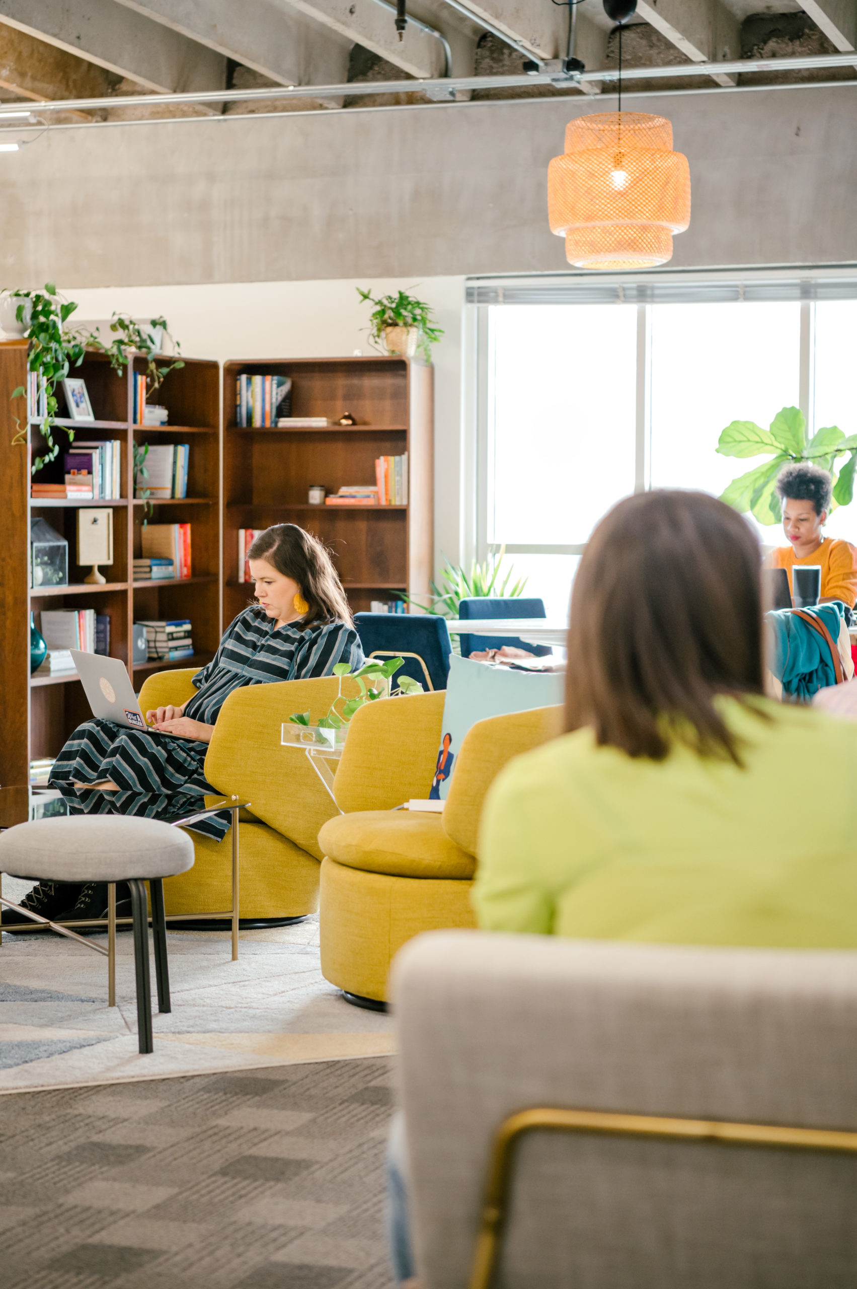 Photo of community workspace with women sitting in lounge chairs working on the computer