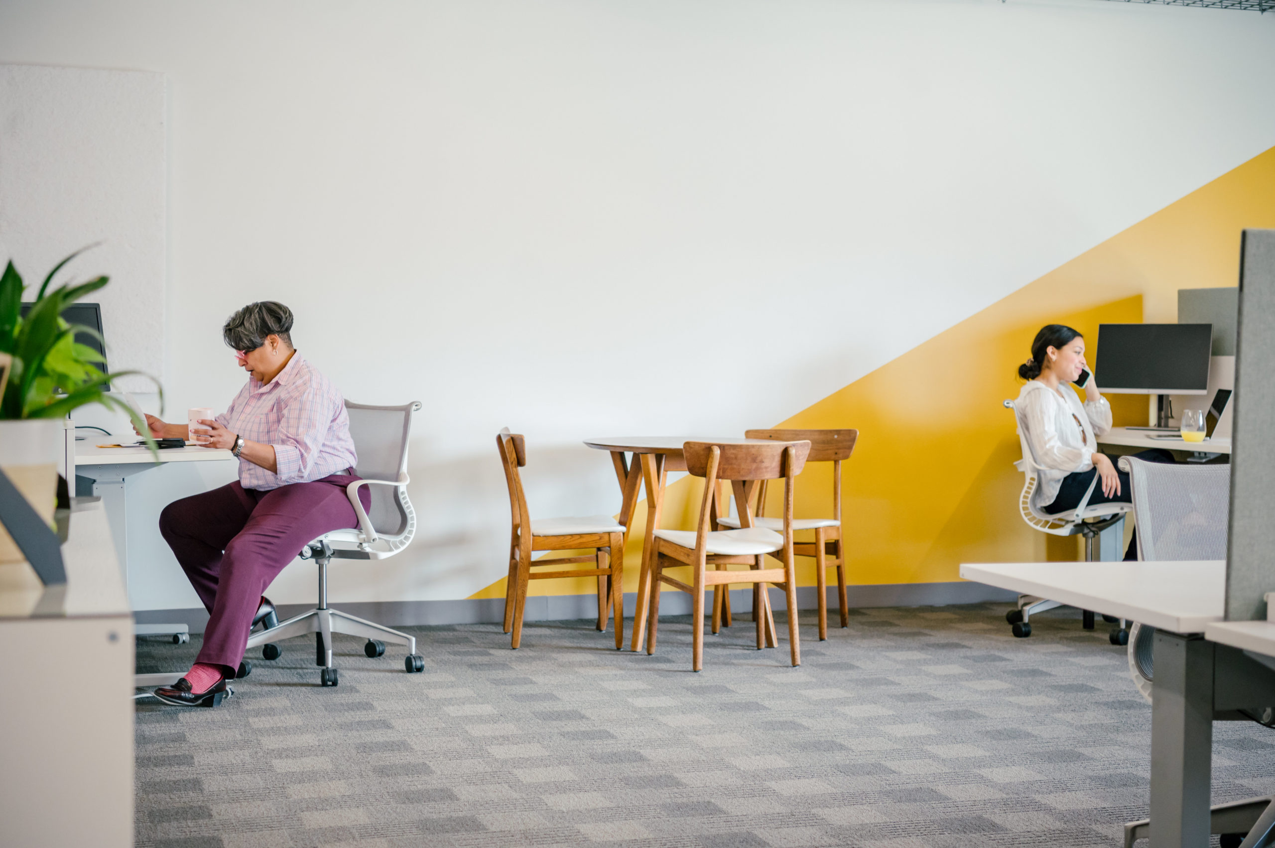 Photo of women working in an office with desks and a table and chairs 