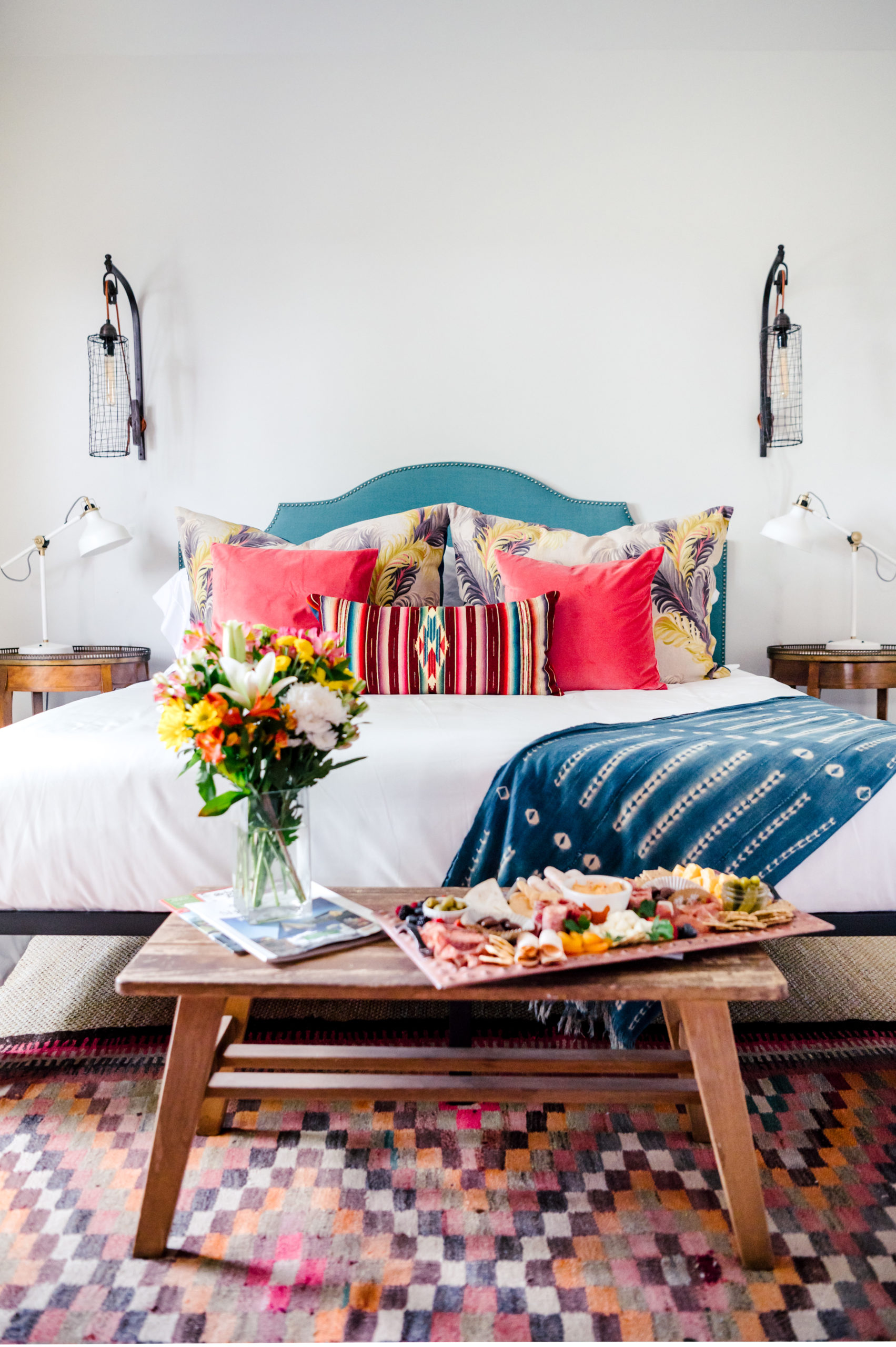 Room with a queen sized bed with colorful pillows and western art hanging on the wall