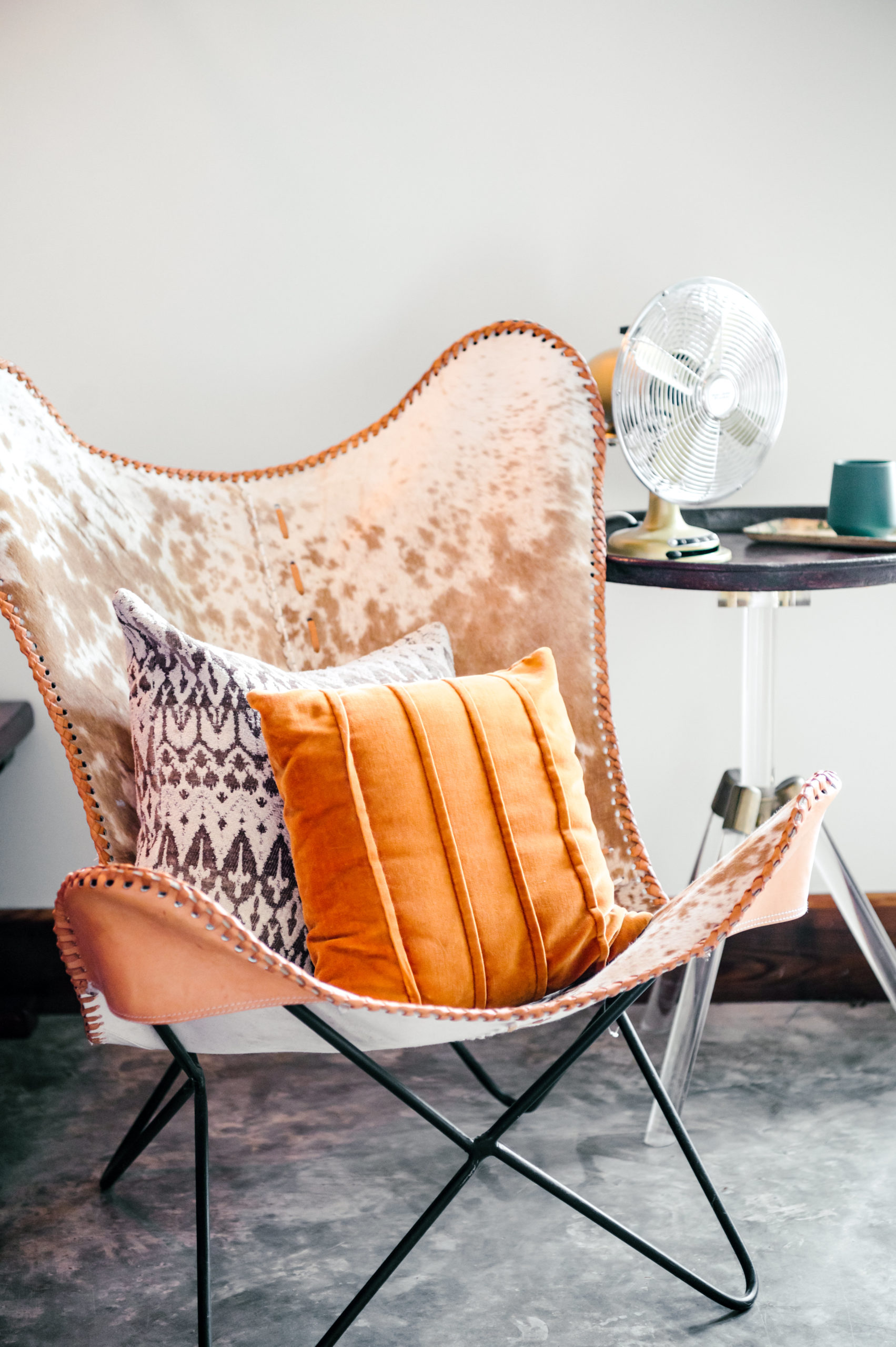 Cow print butterflie chair with orange and stiped pillows 