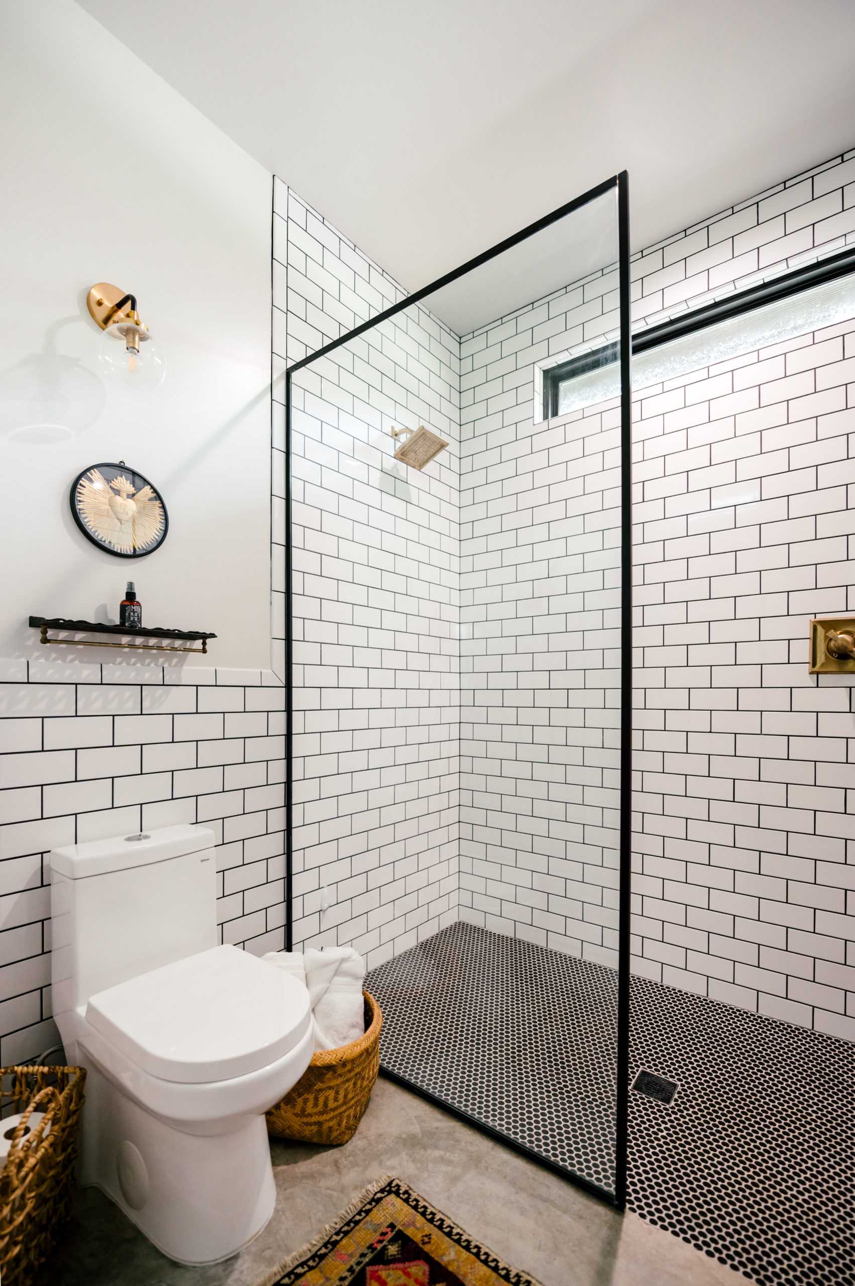 White toilet and open shower with white and black wall tile 