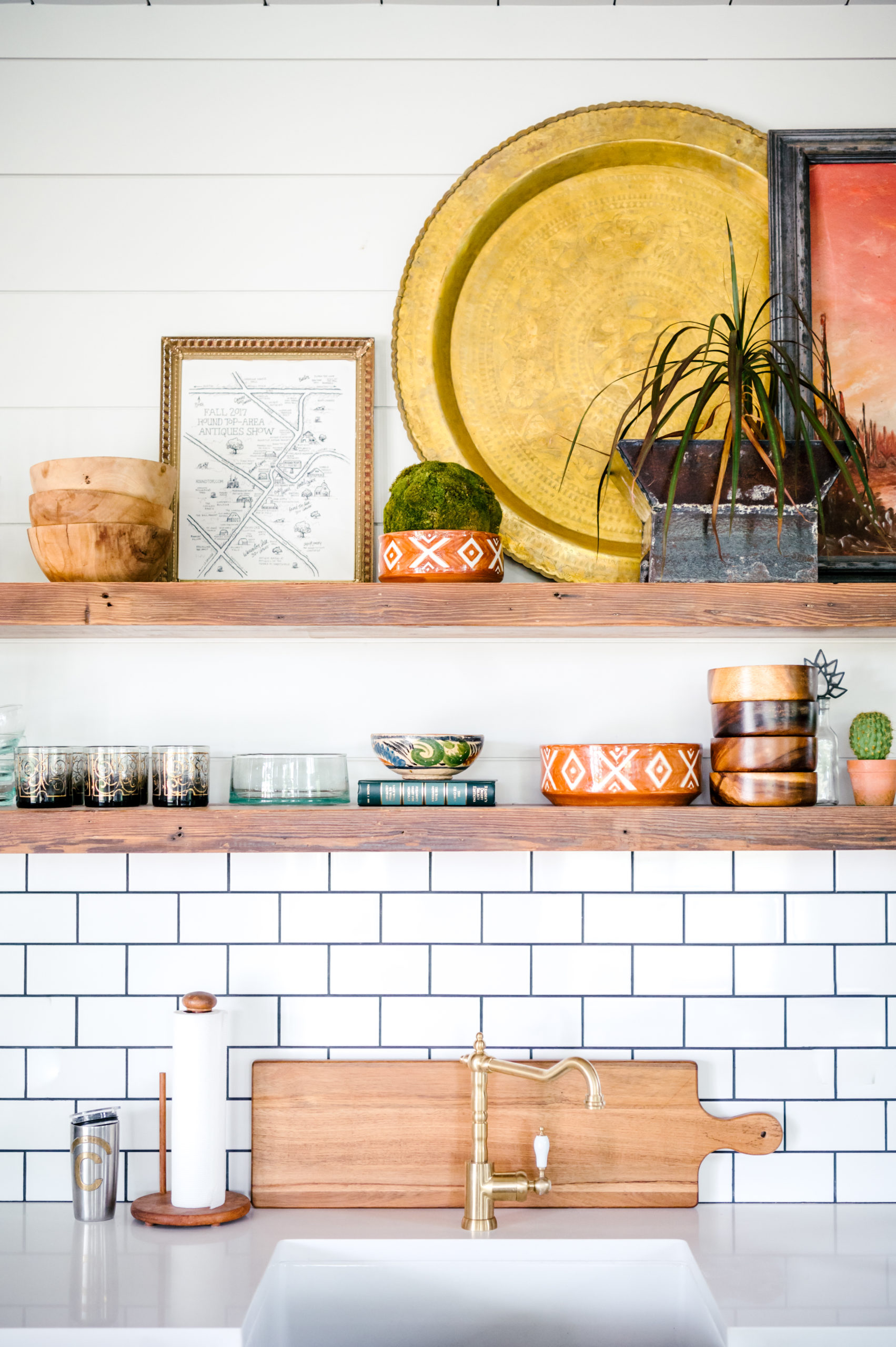 Kitchen counter with black and white wall tiles and shelves with plates and bowls