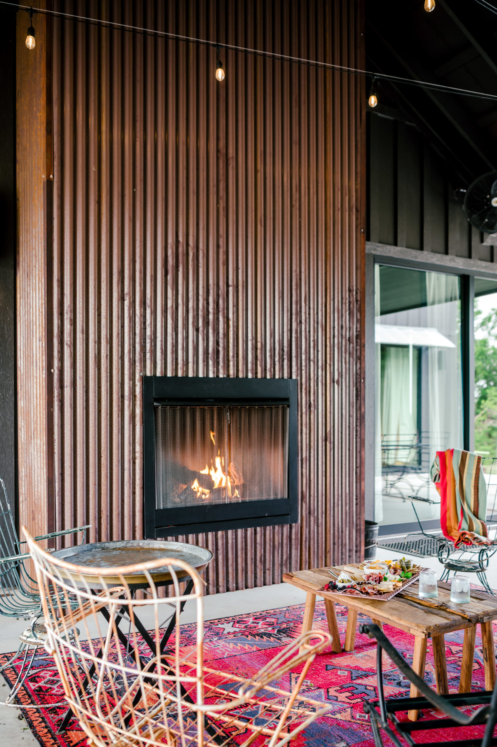 Outside fireplace with exterior lounge furniture and red western rug