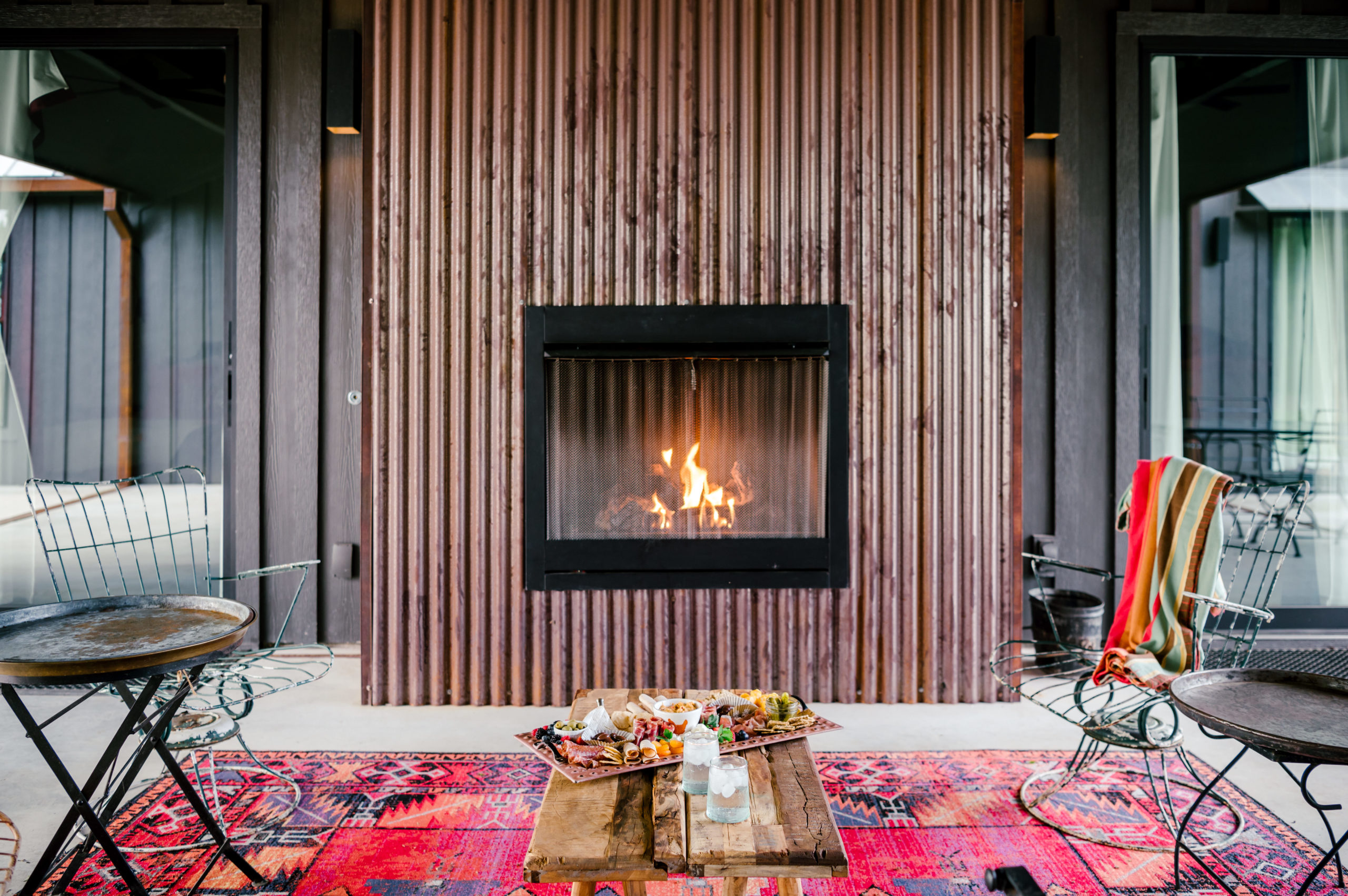 Outside fireplace with exterior lounge furniture and red western rug