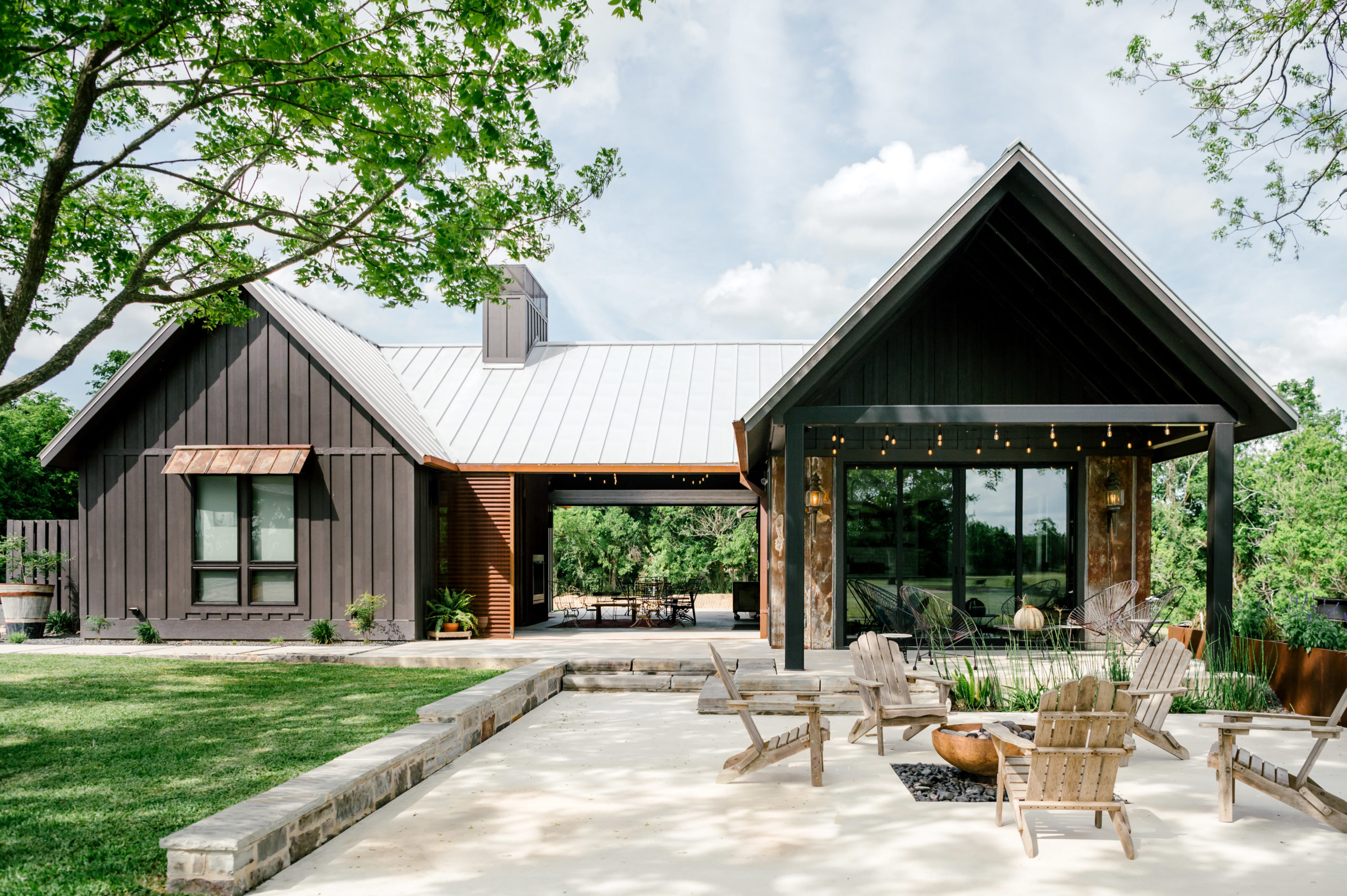 Airbnb exterior with dark exterior paint mixed with wood and rusted-looking metal and metal outdoor lounge furniture 