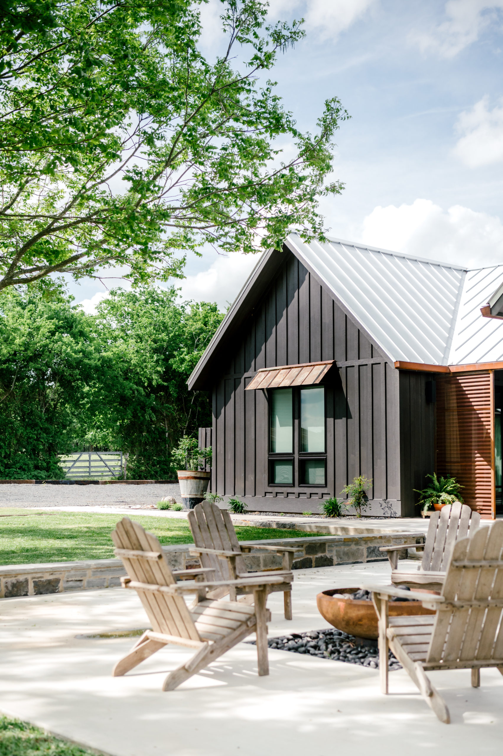 Airbnb exterior with dark exterior paint mixed with wood and rusted-looking metal and metal outdoor lounge furniture 