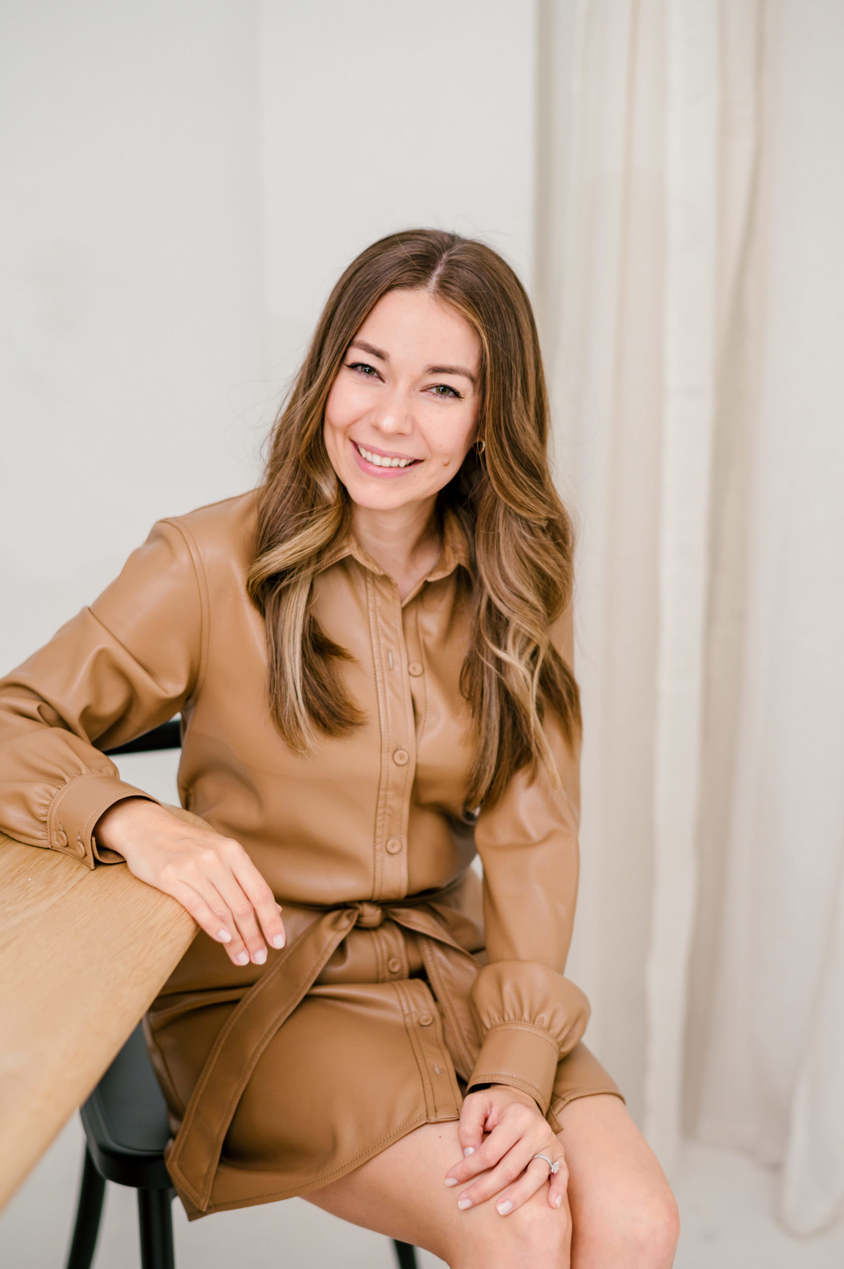 Woman smiling in a brown leather dress 