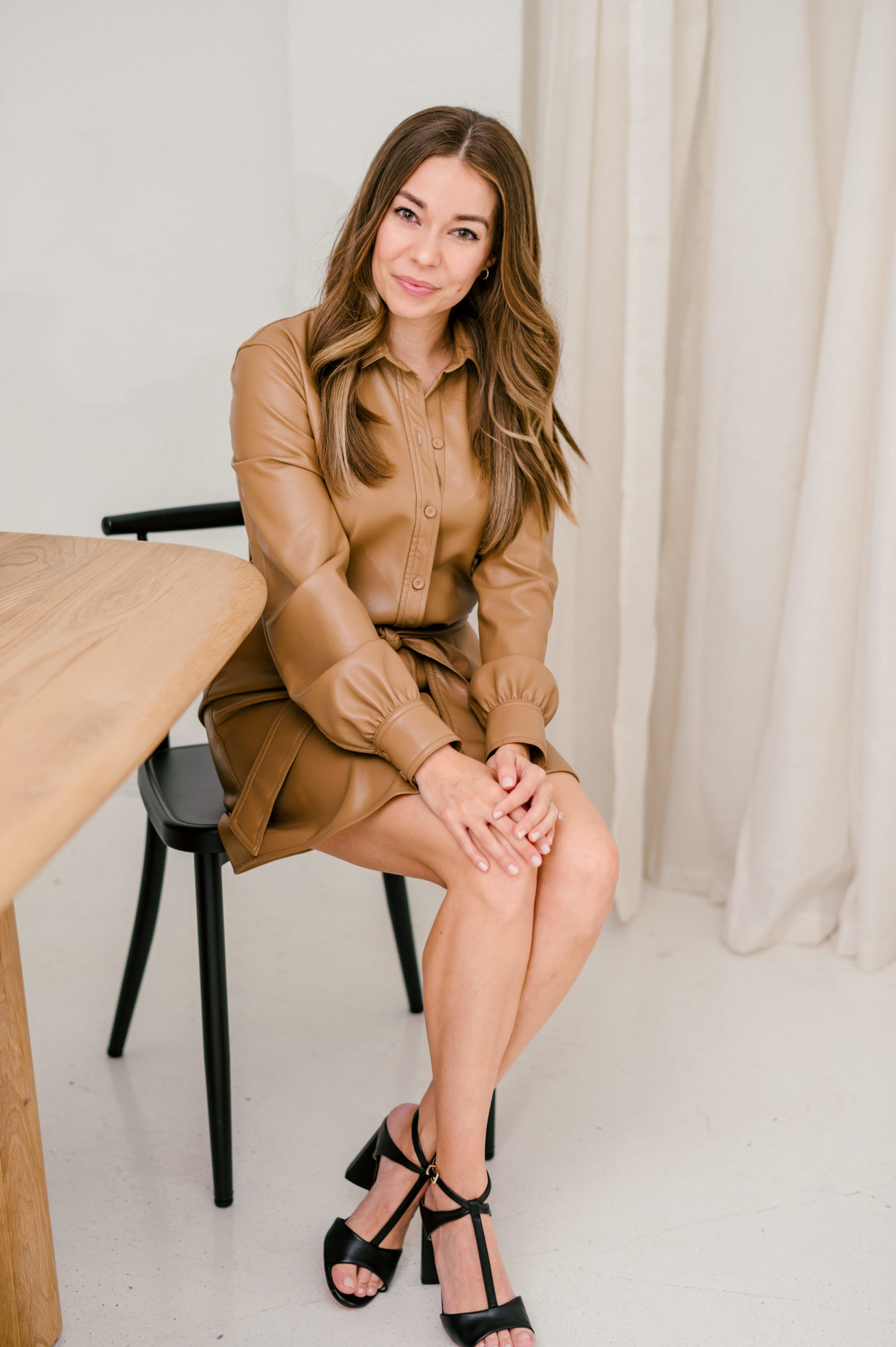 Woman in a brown leather dress sitting down smiling and posing for her brand photography photos