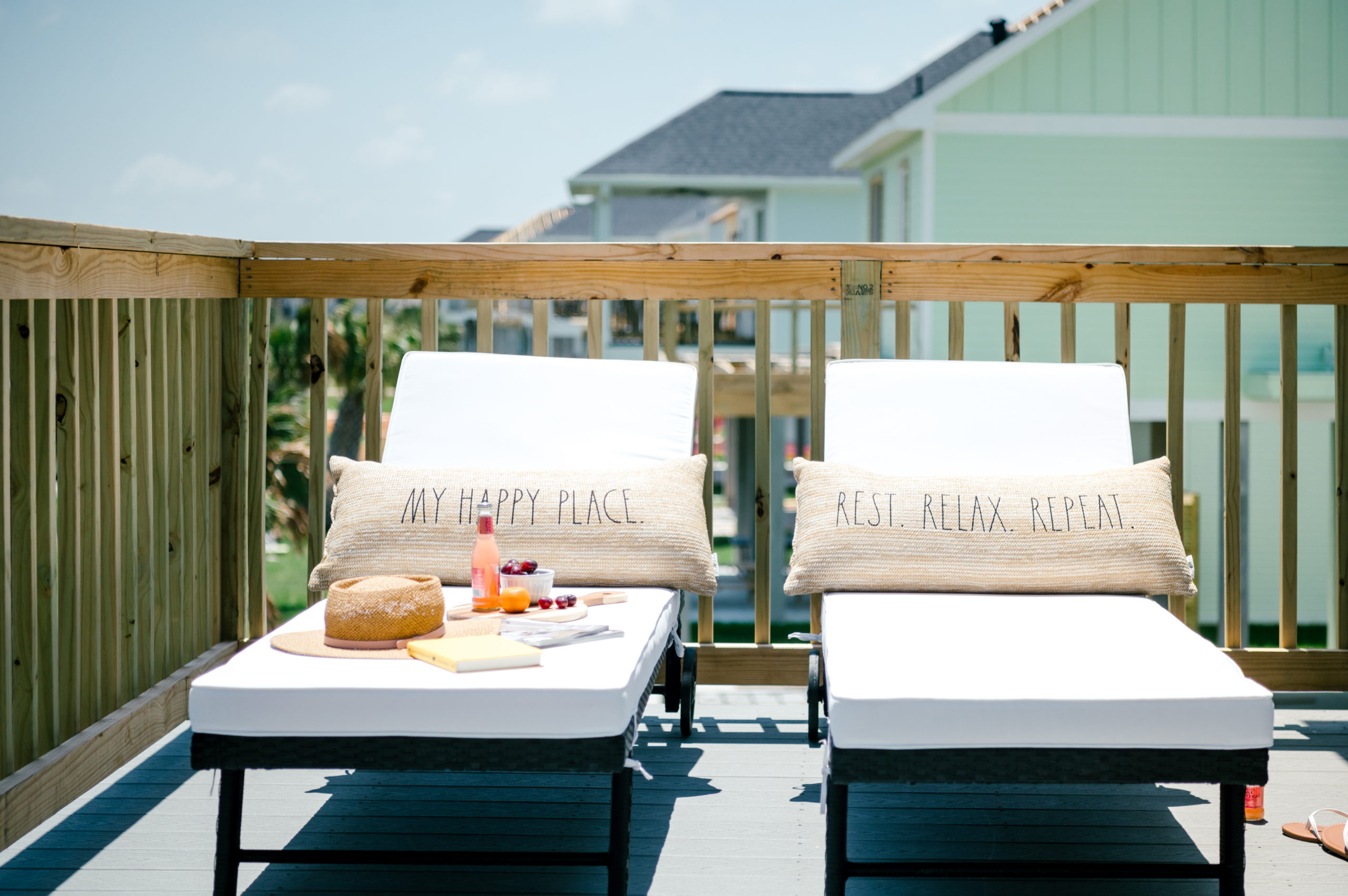 Vacation Rental Photography photos ofOutdoor lounge chairs with tan pillows reading "Happy place" sitting on the balcony