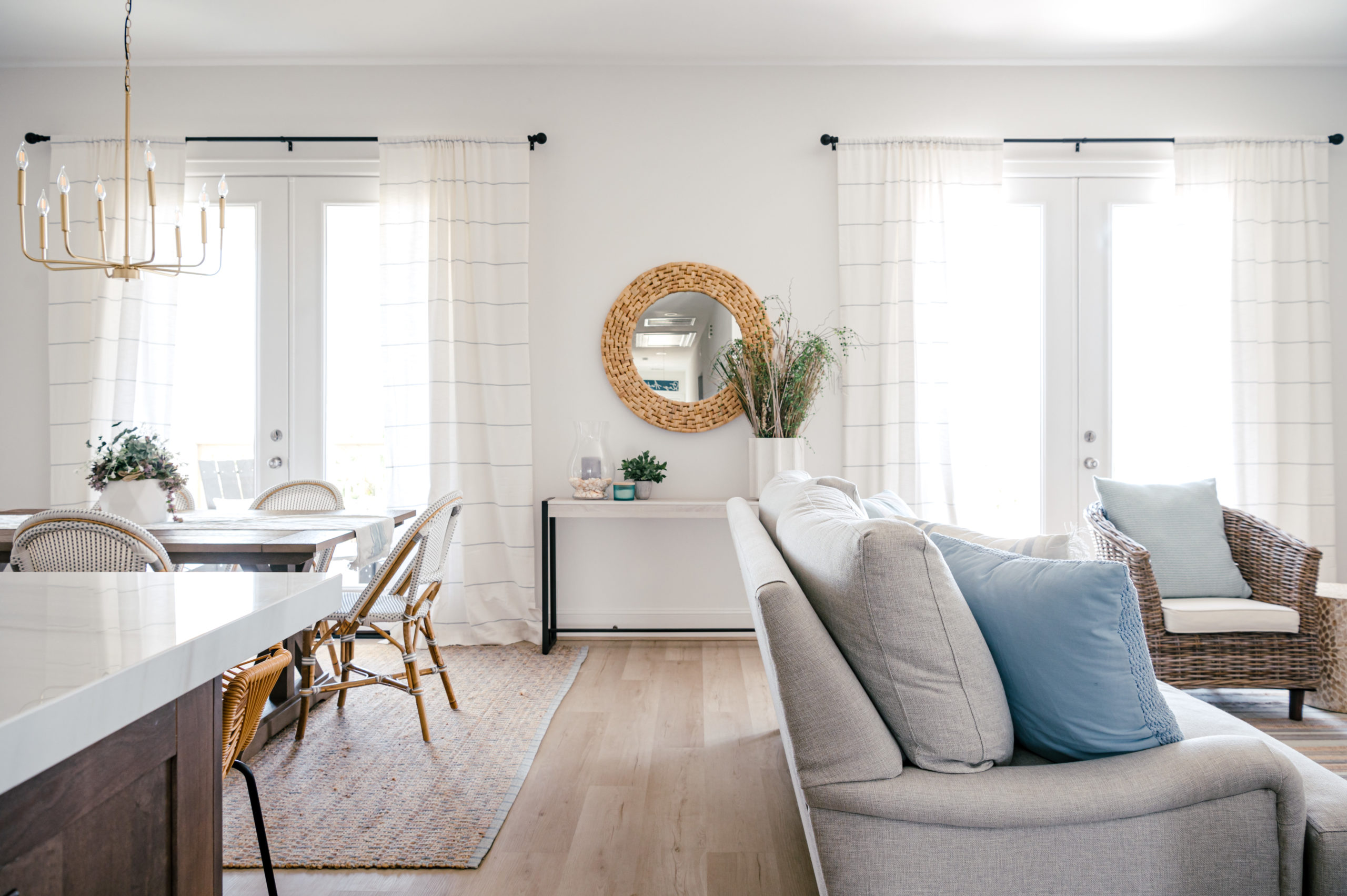 Beach house kitchen dining room combo and living room interior design and decor, with a grey couch and white and blue decorative pillows