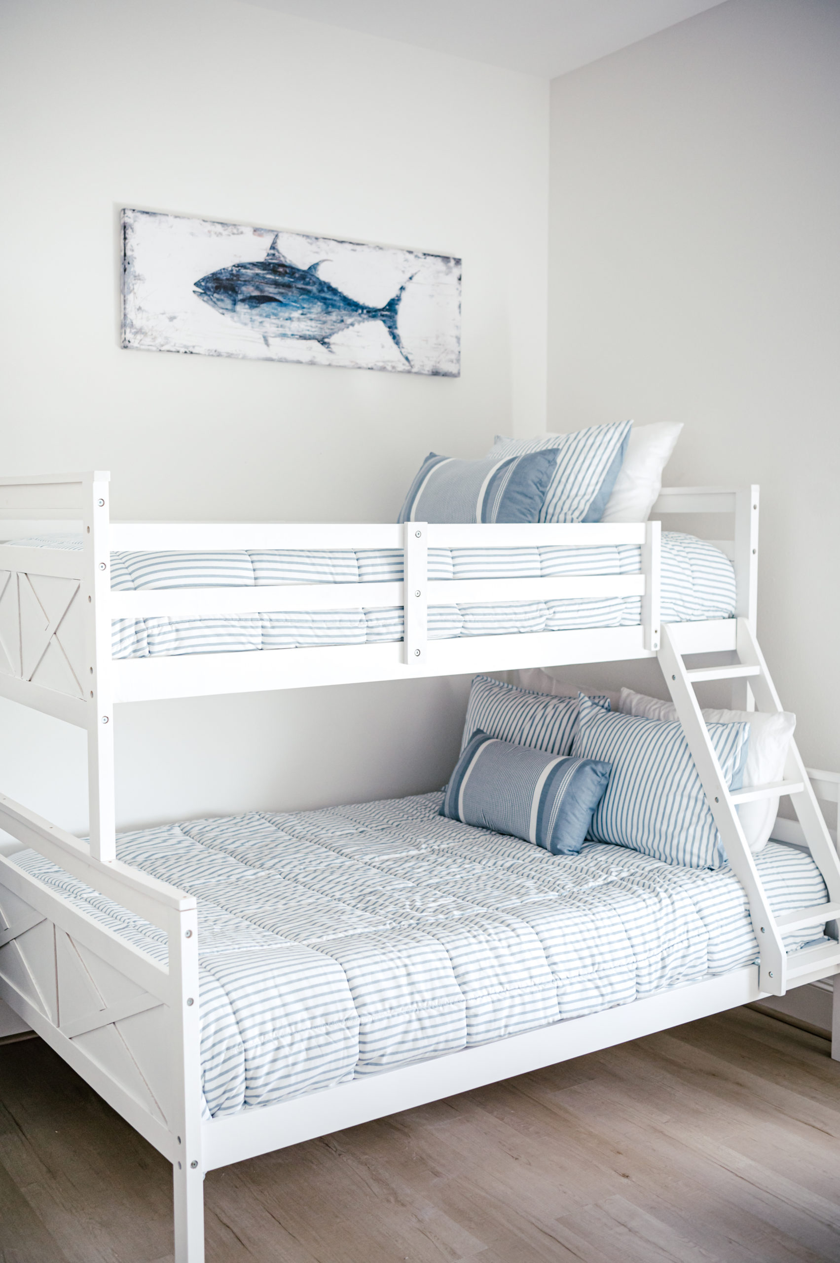 White wooden bunk beds with white and blue bed covers and pillows