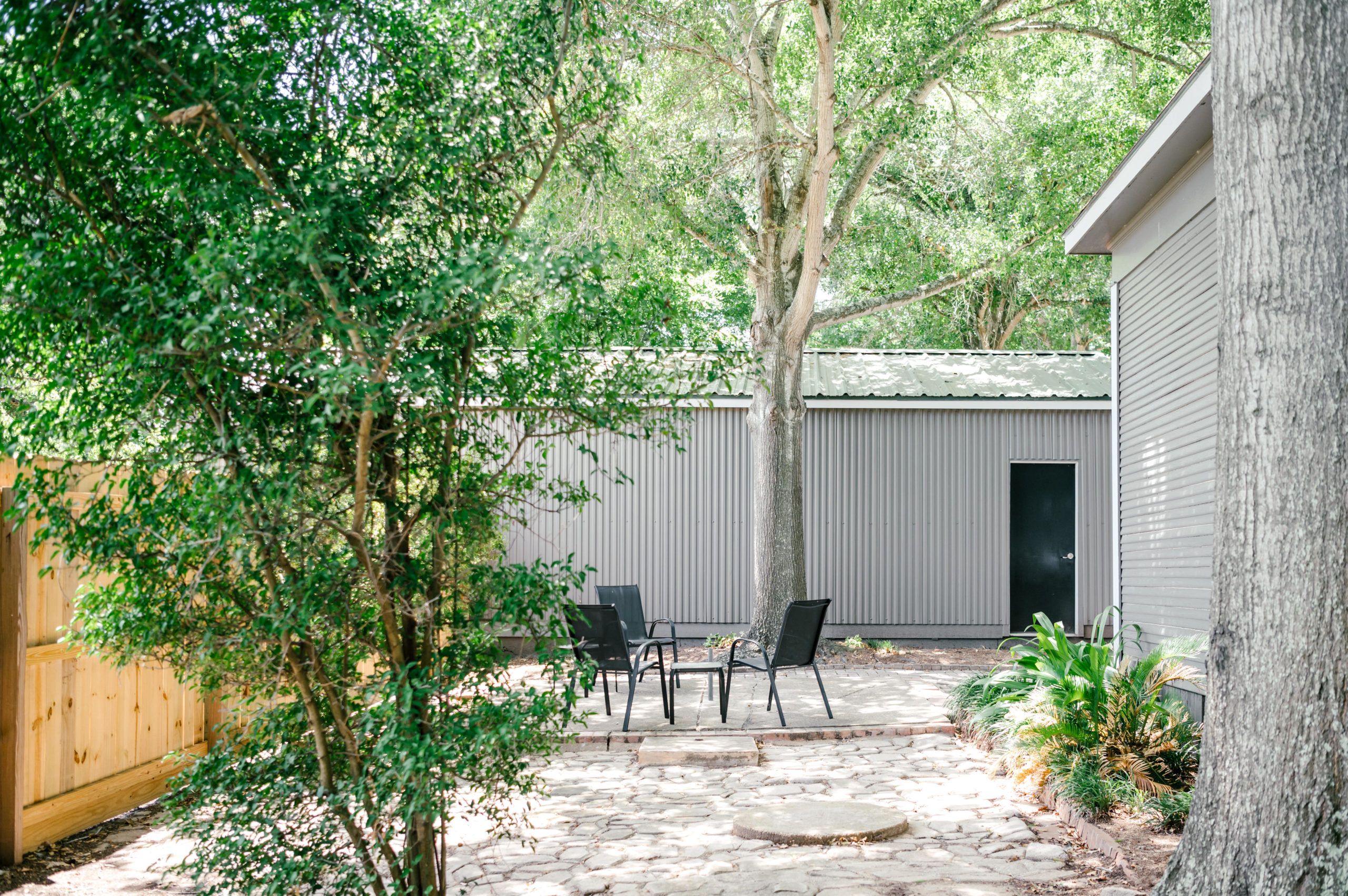 Backyard with outside metal chairs and table surrounded by trees