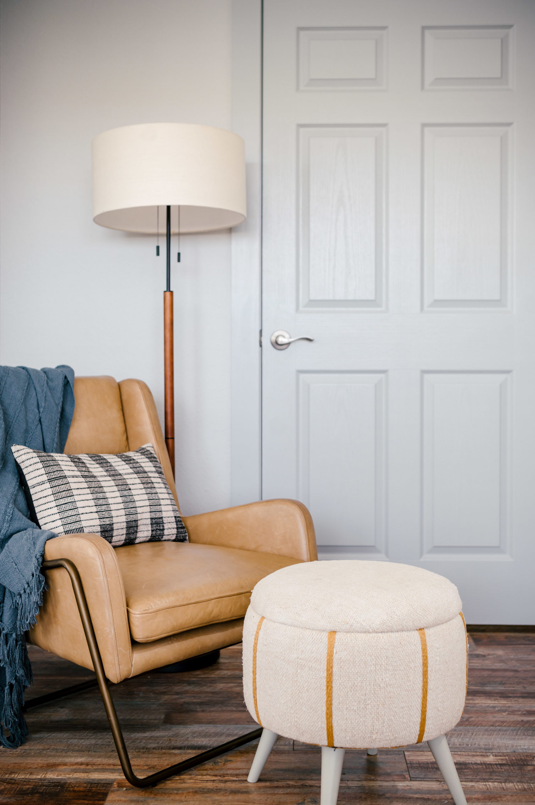 Interior Design Photography of Leather armchair with striped pillow and blanket and foot rest