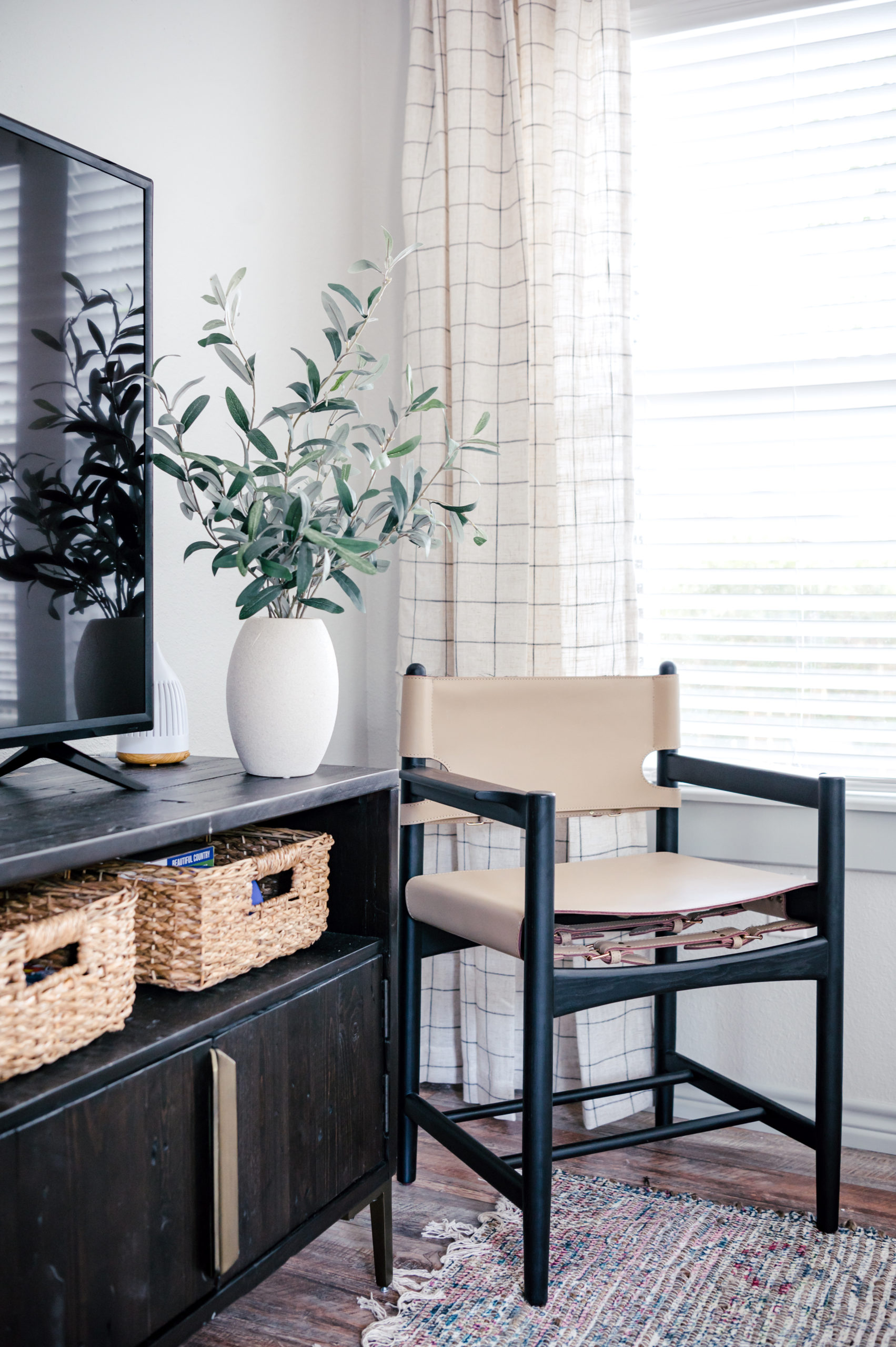 Sling side chair sitting next to black tv on a black tv console