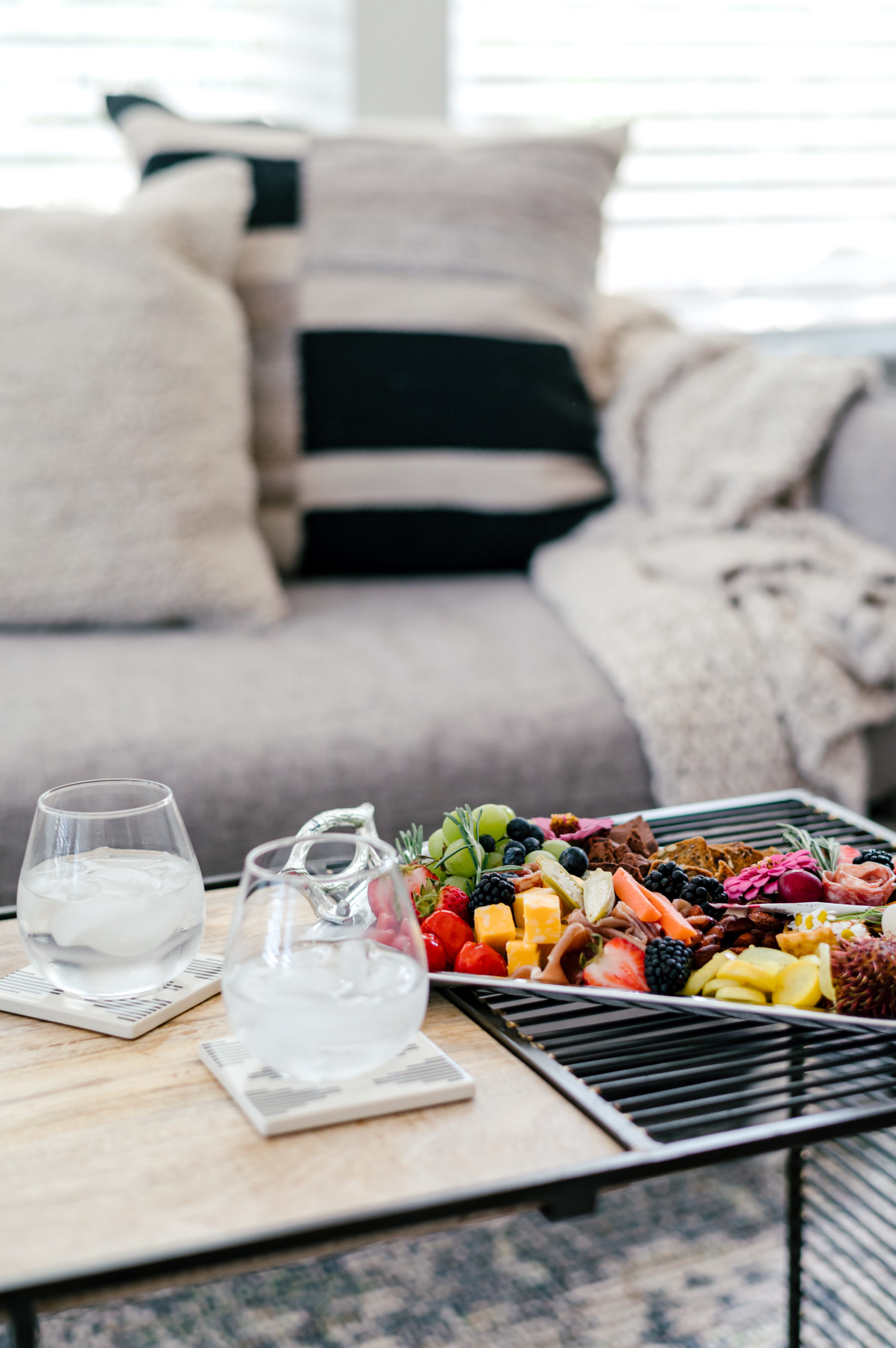 Charcuterie board with two classes of ice water on living room table