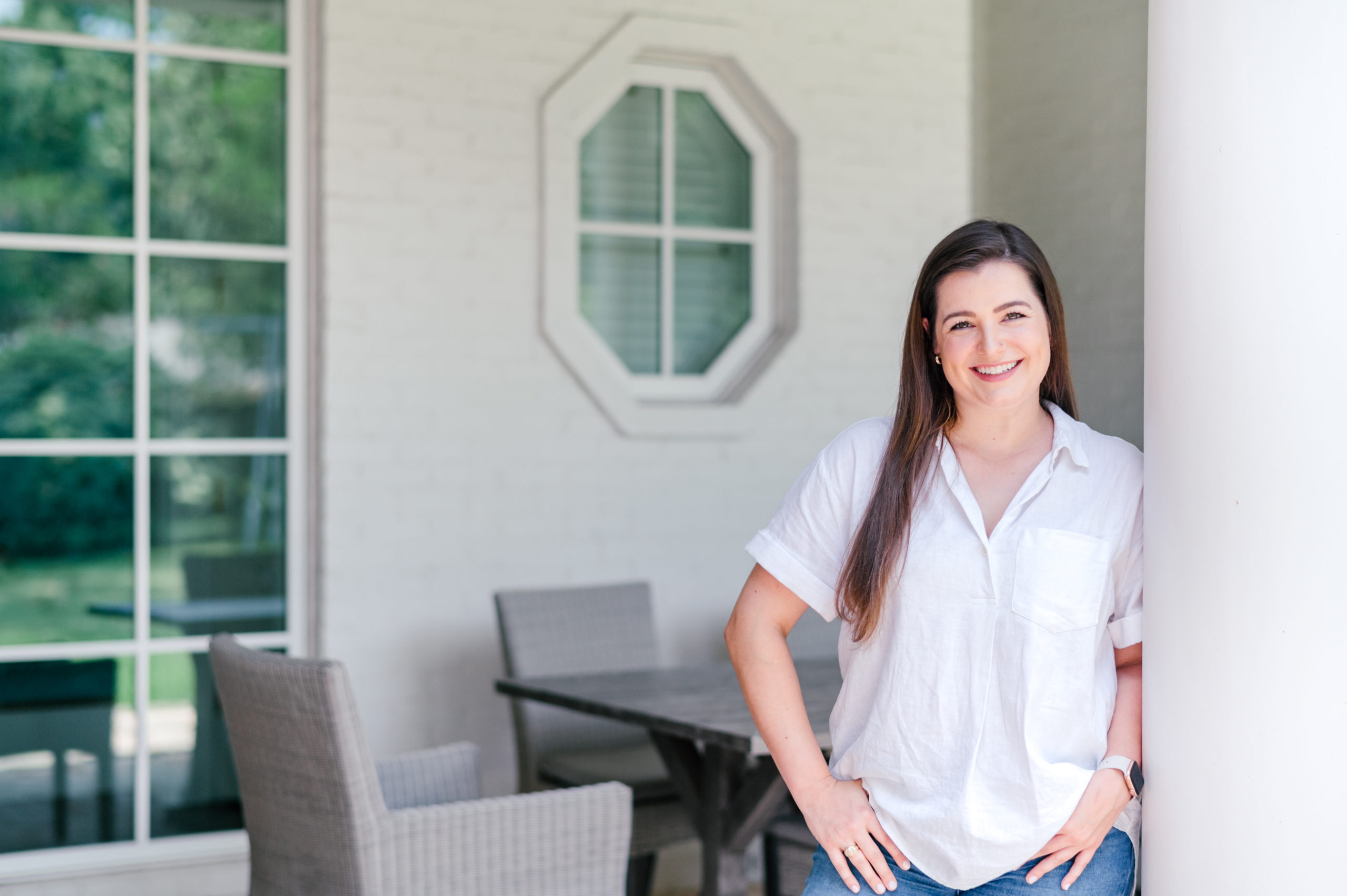 Photo of women standing on front porch smiling with her hands in her pockets by a Houston Brand Photographer