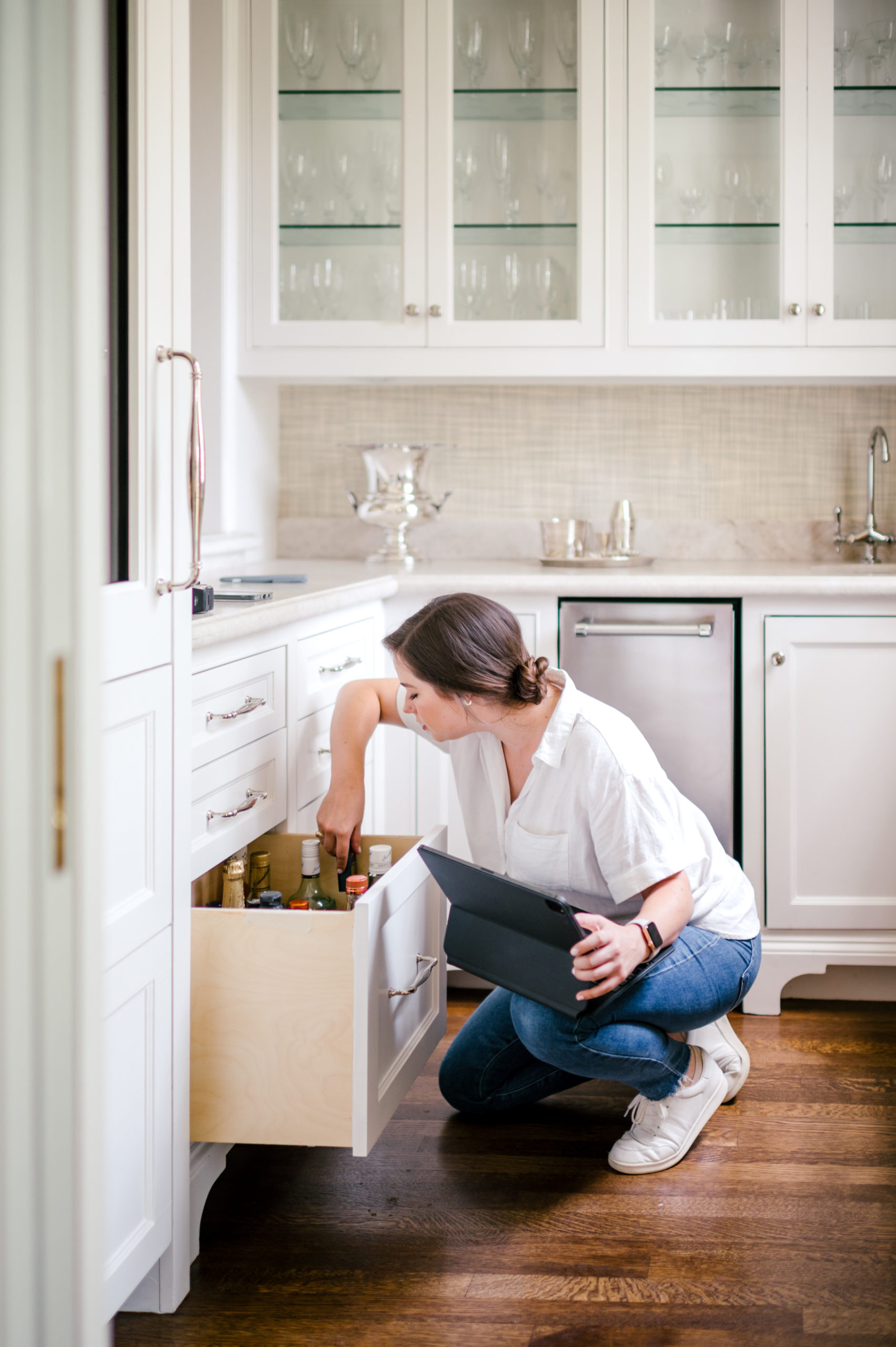 Woman organizing kitchen drawer full of alcoholic beverages 