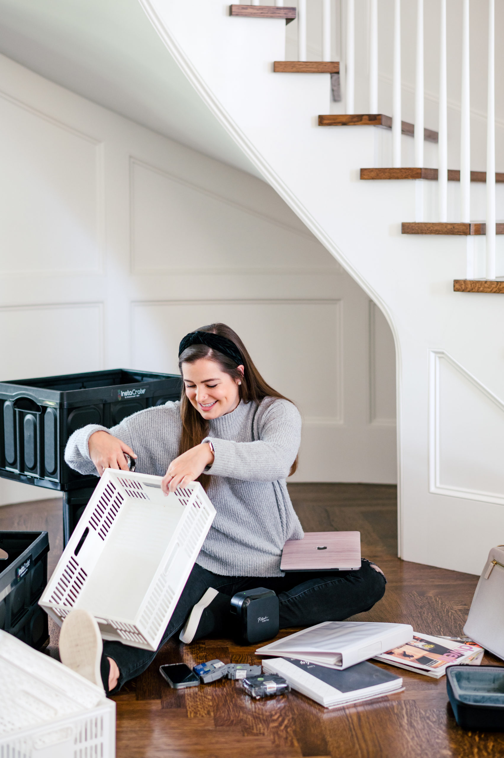 Woman sitting on hard wood floor organizing boxes and files