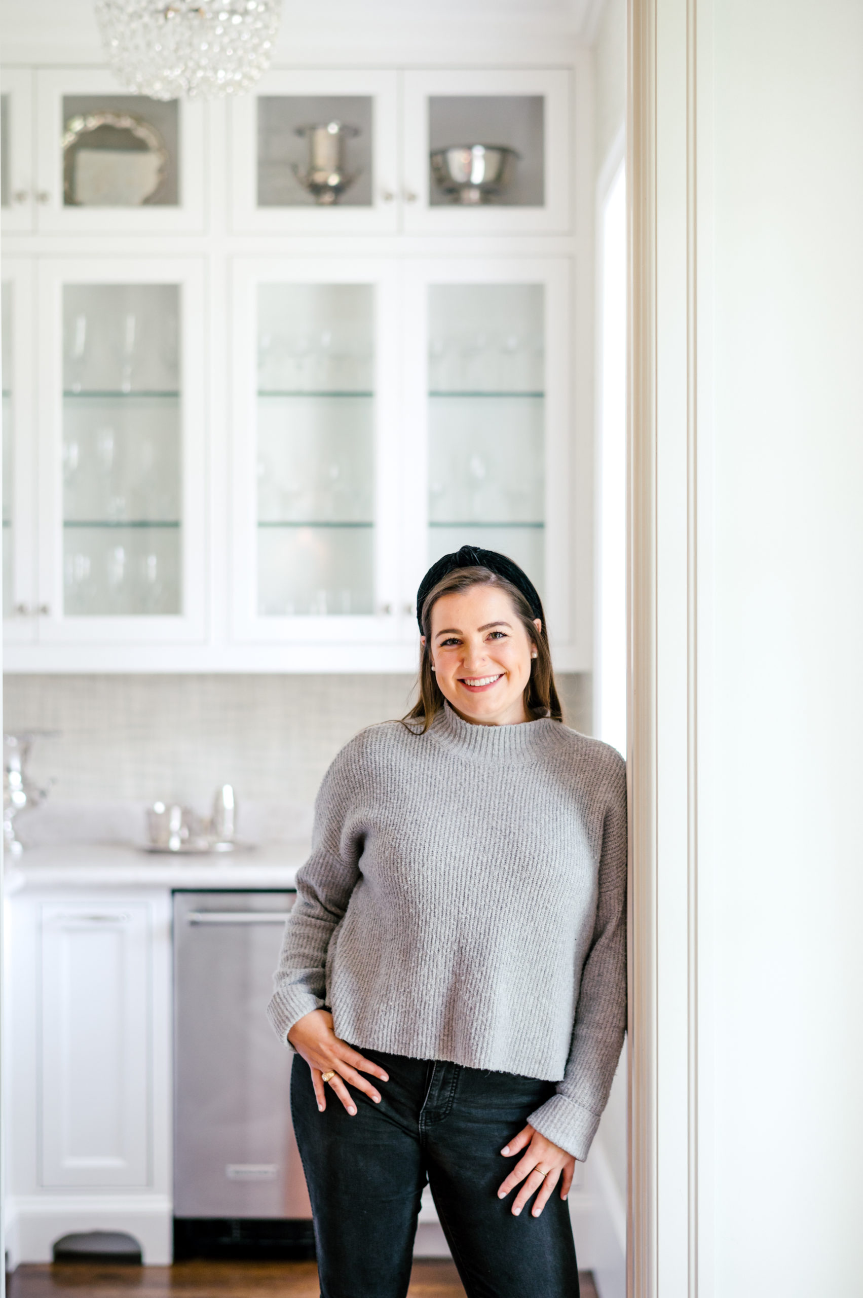 Photo of a Woman standing in kitchen smiling in dark jeans and grey sweater Houston Brand Photographer
