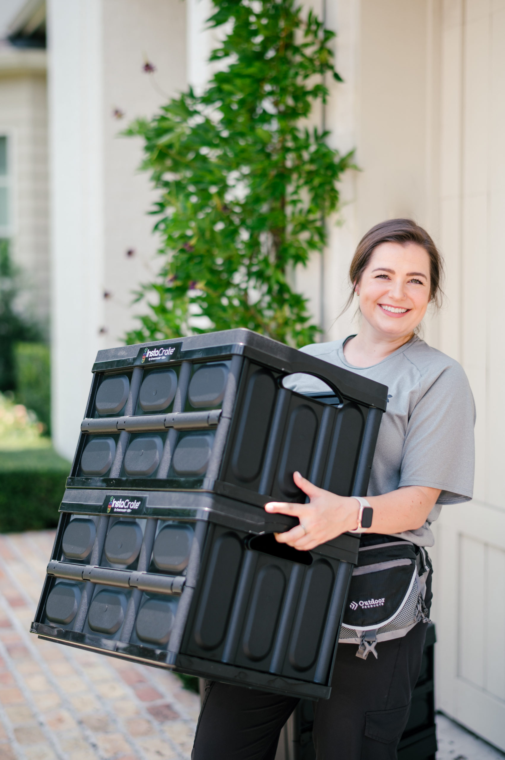 Woman smiling and holding onto black boxes 