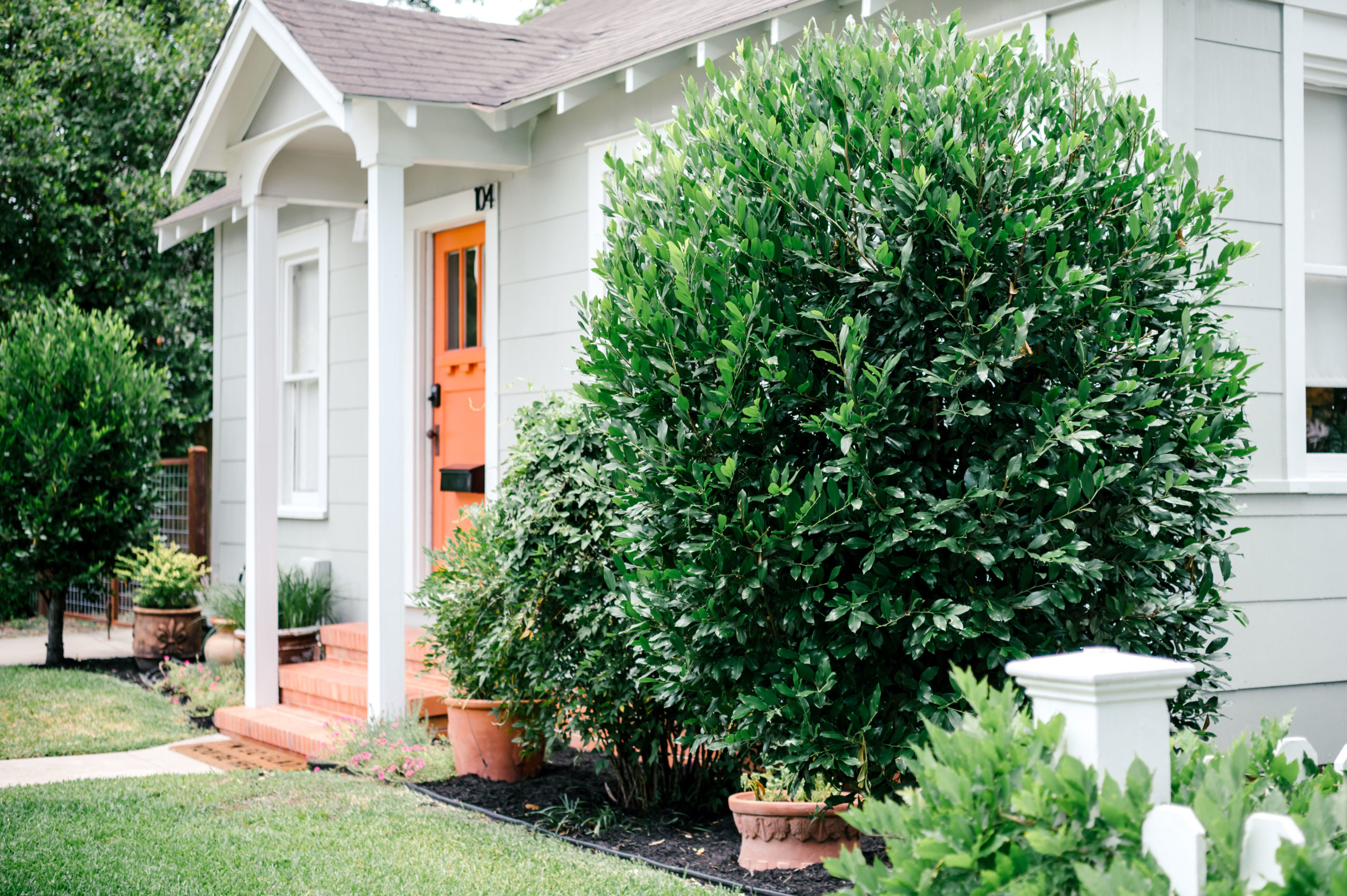 Short-term Rental Photos of the exterior of a grey one story home with an orange door and steps