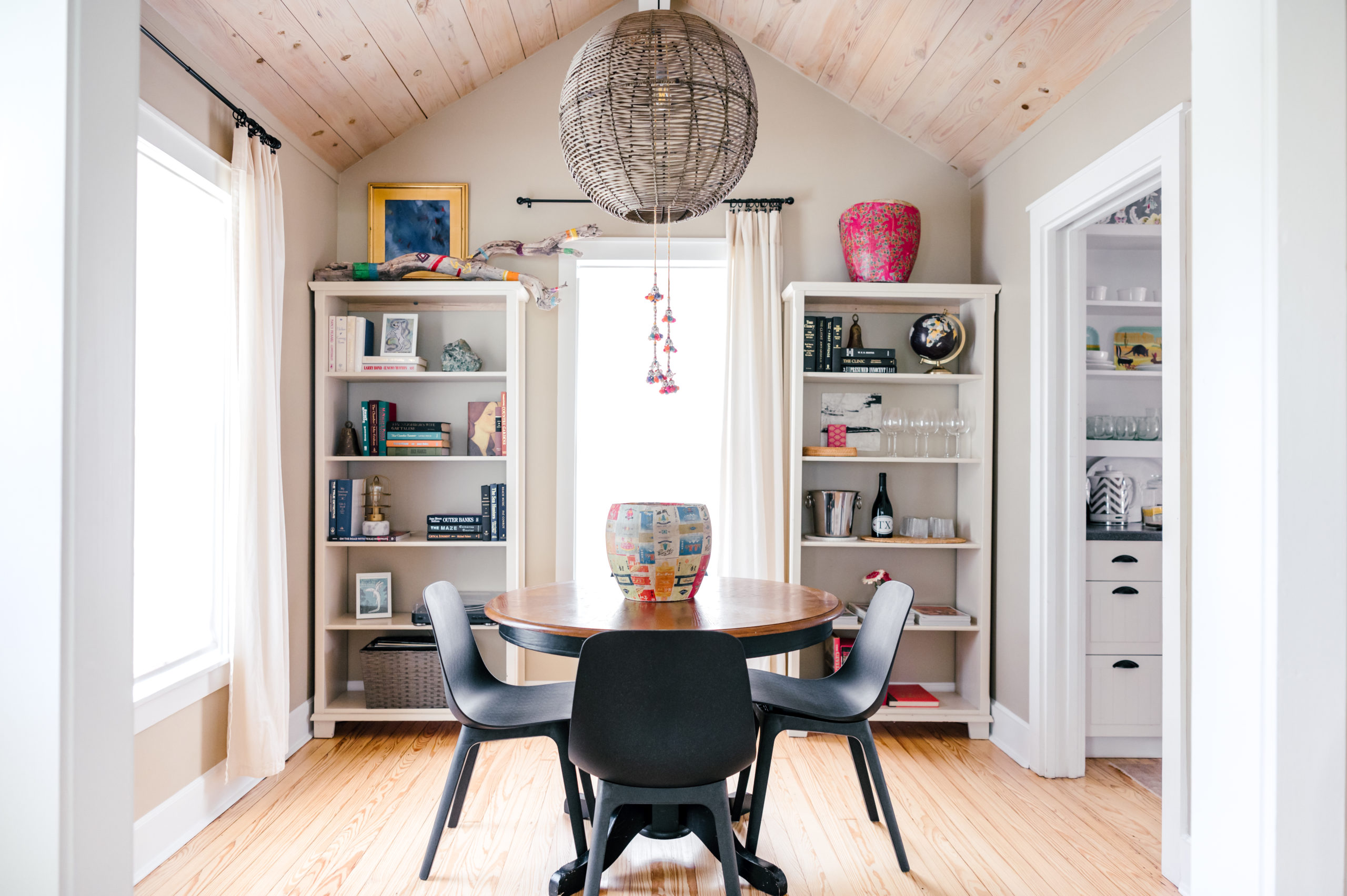 Black dining room table and chairs in dining room with shelving full of dishware