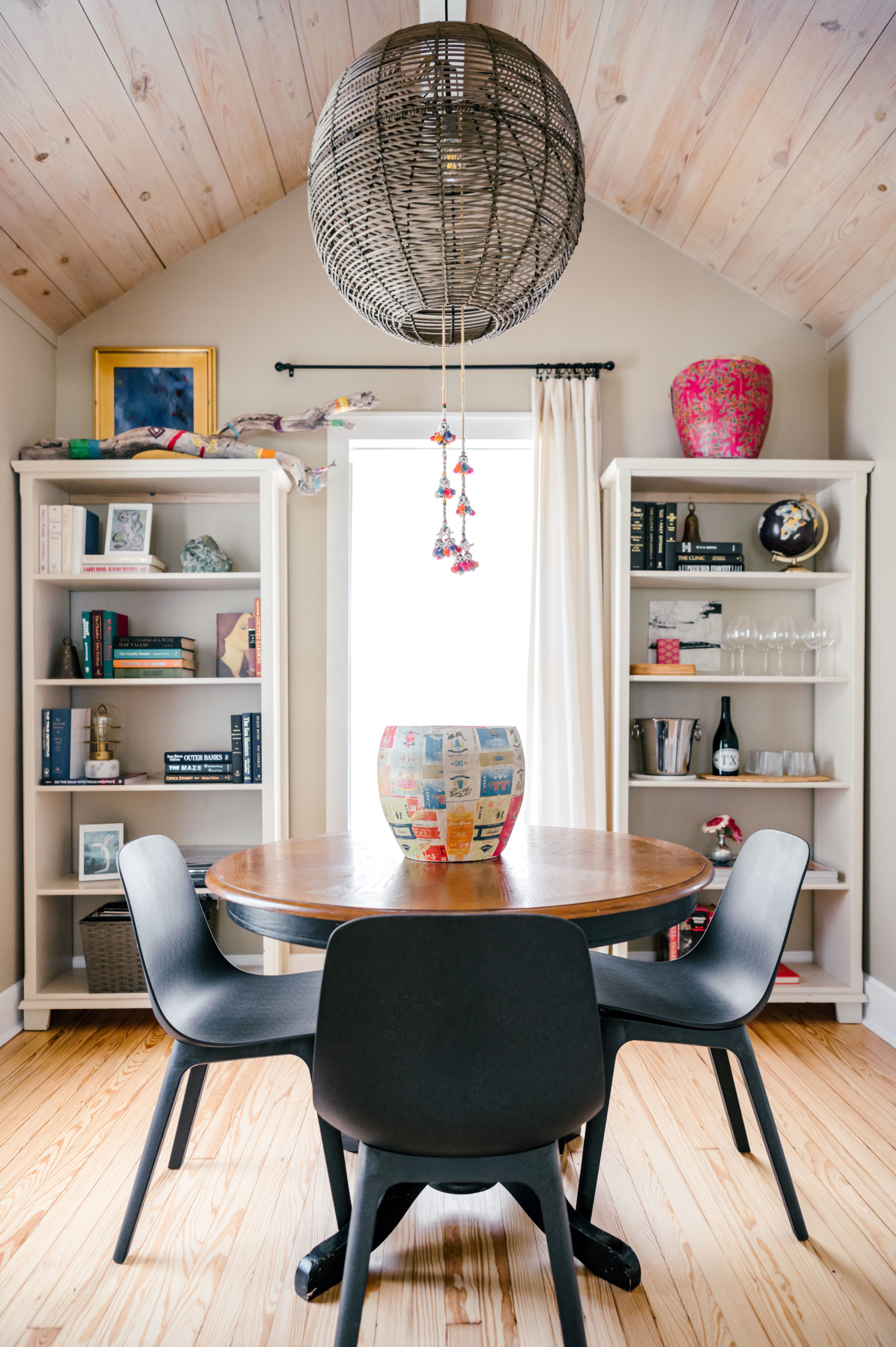 Black dining room table and chairs in dining room with shelving full of dishware and books
