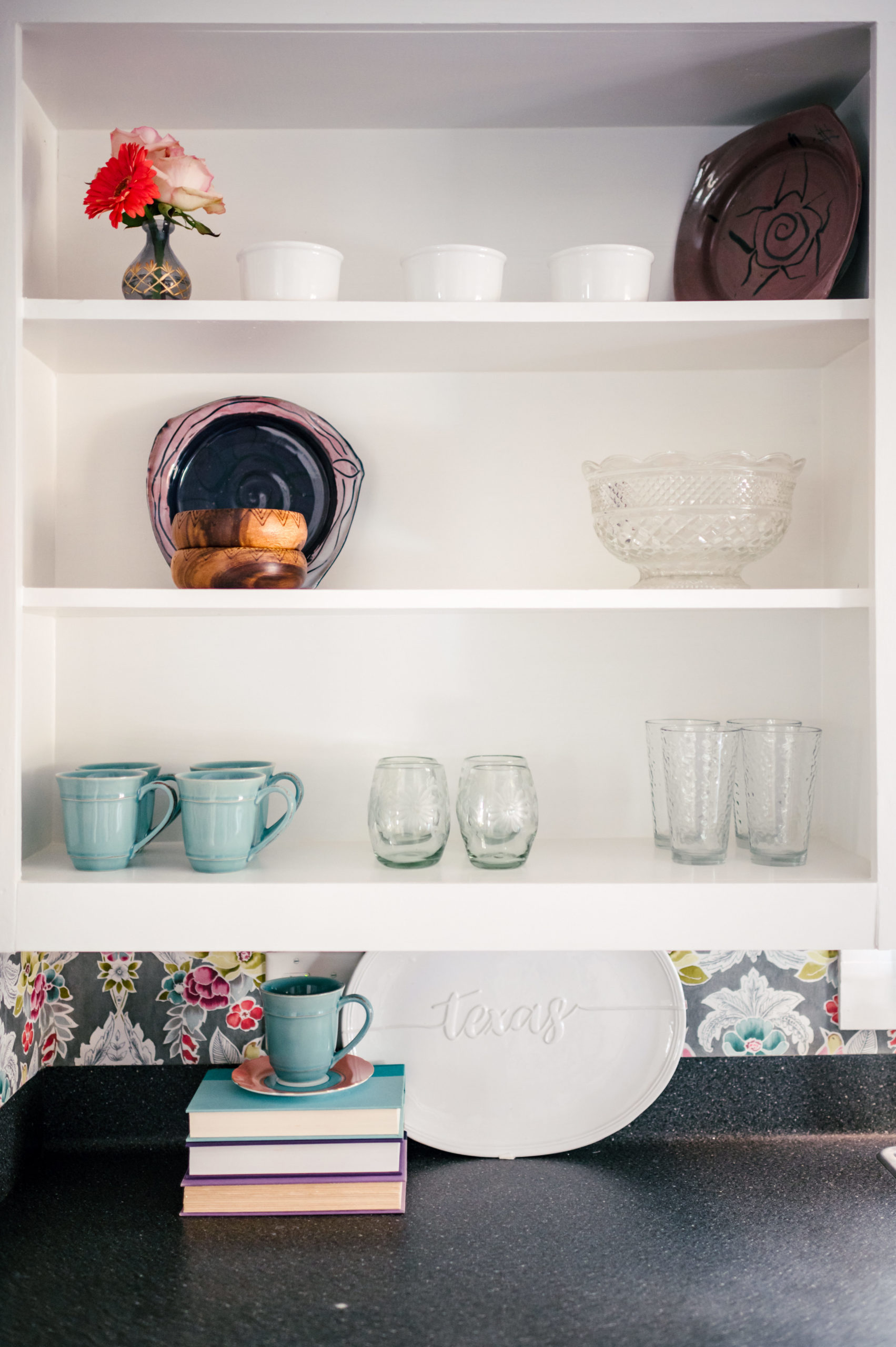 Kitchen shelving with dishware and countertop with a blue toaster 