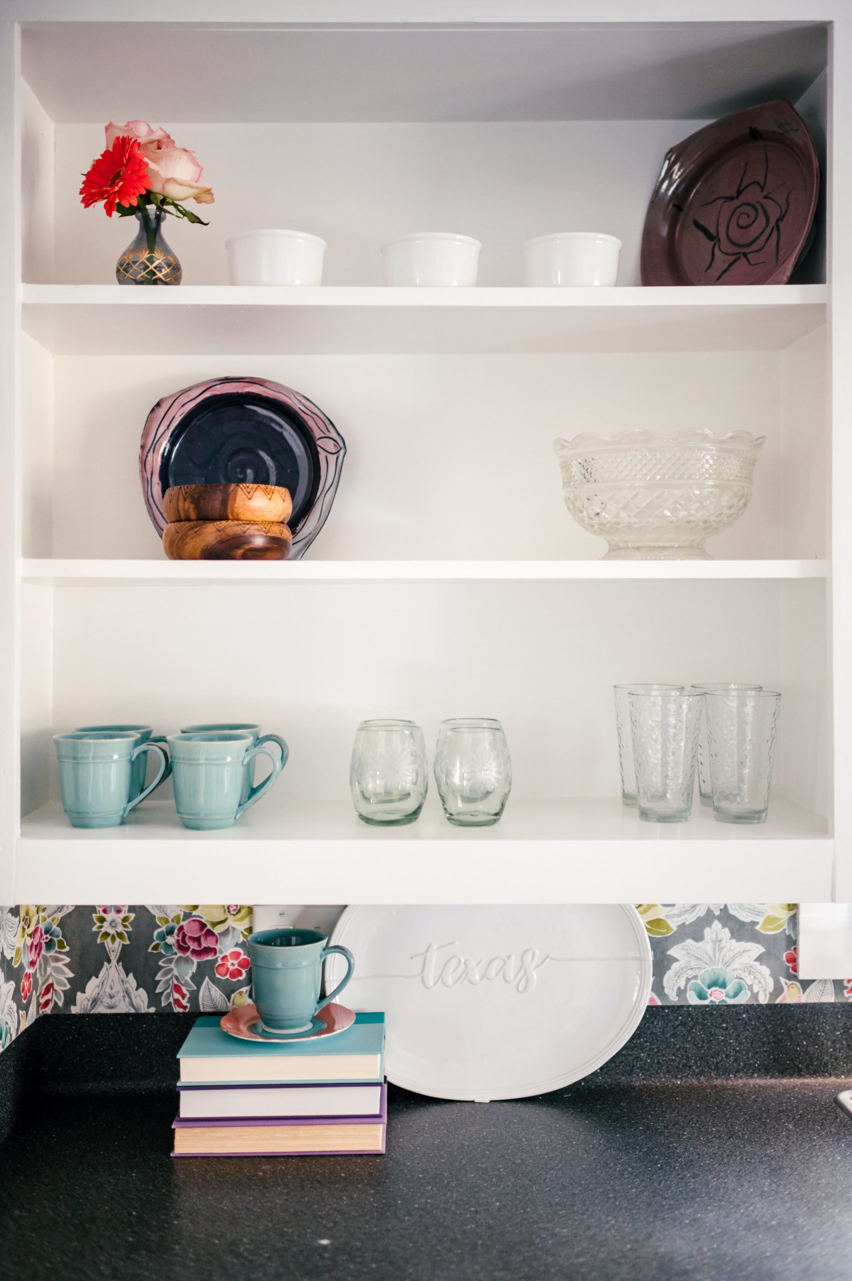 Kitchen shelving with dishware and countertop with a blue toaster