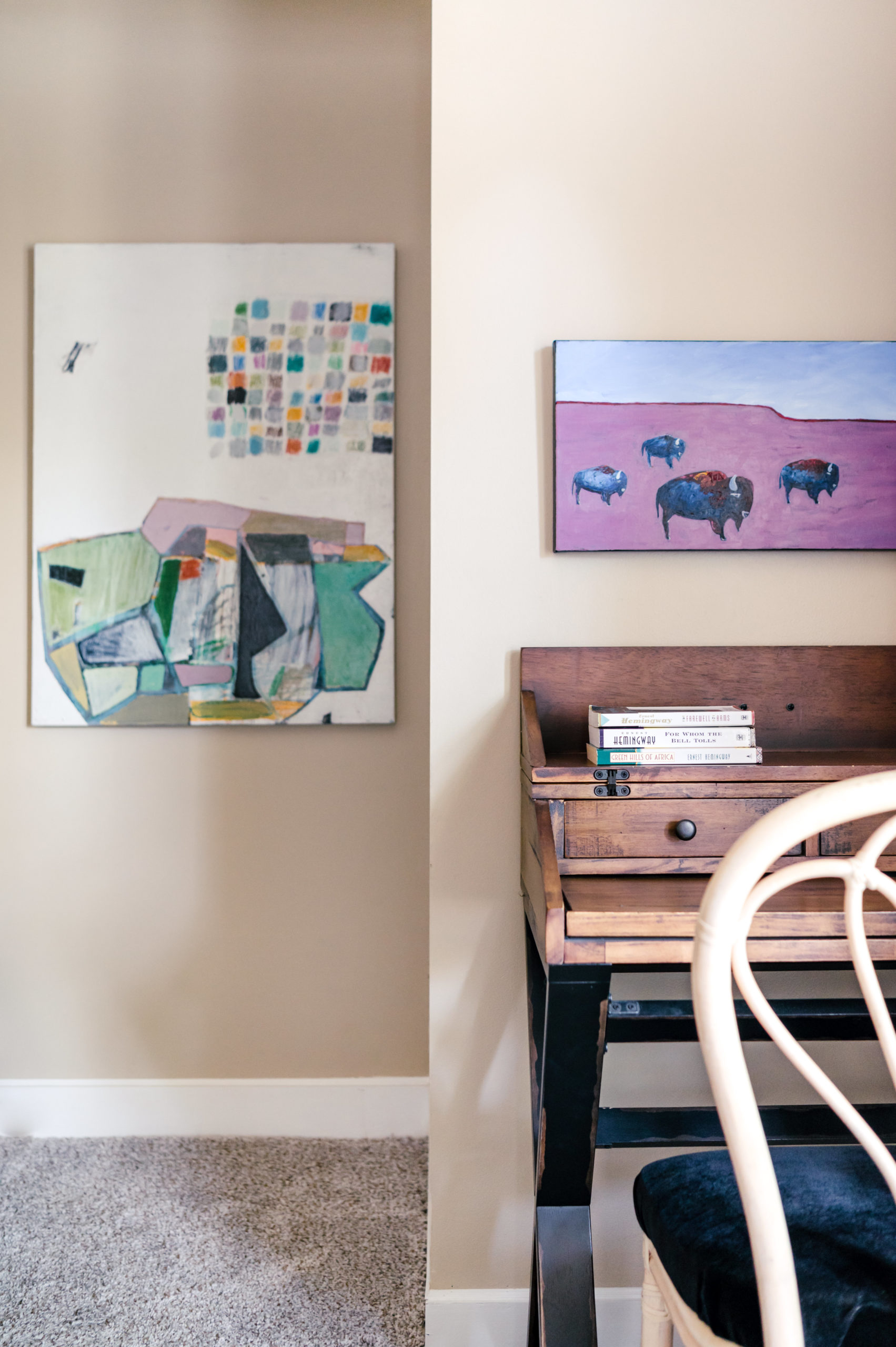 Office with wooden desk and chair, with wall art hanging 