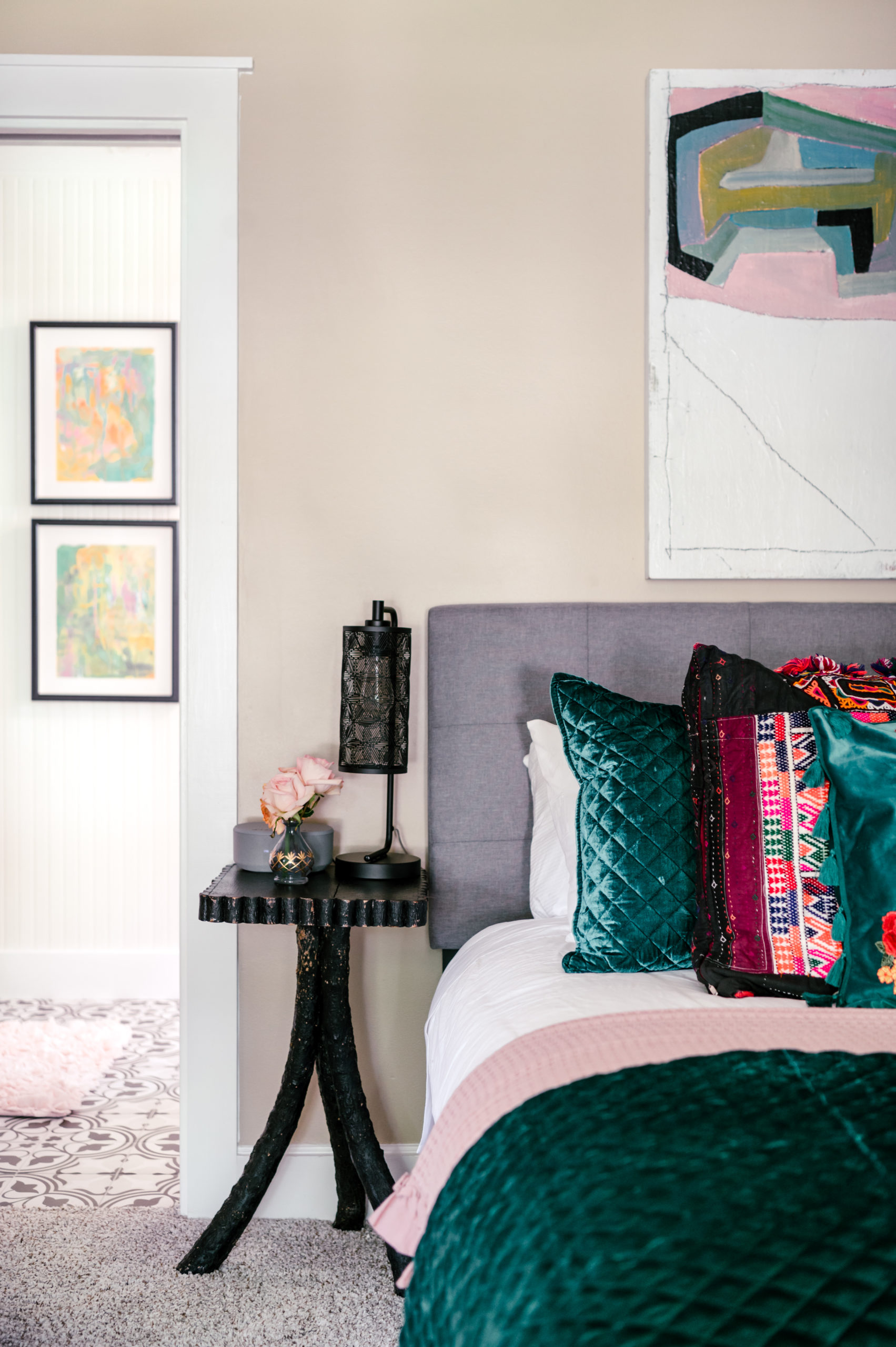 Queen bed covered in a green velvet comforter with green, red and pink pillows