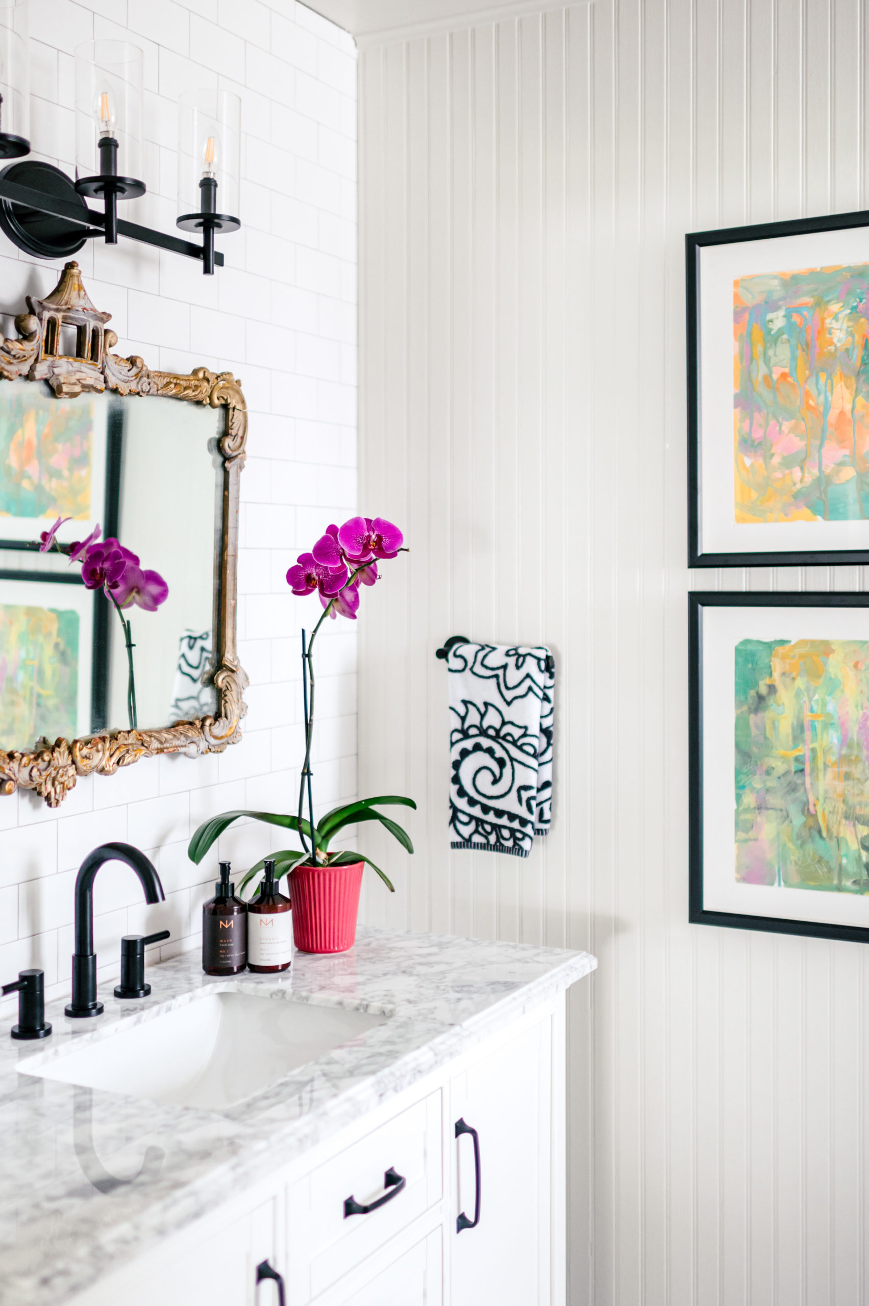 Marble bathroom counter with a mirror and wall art hanging