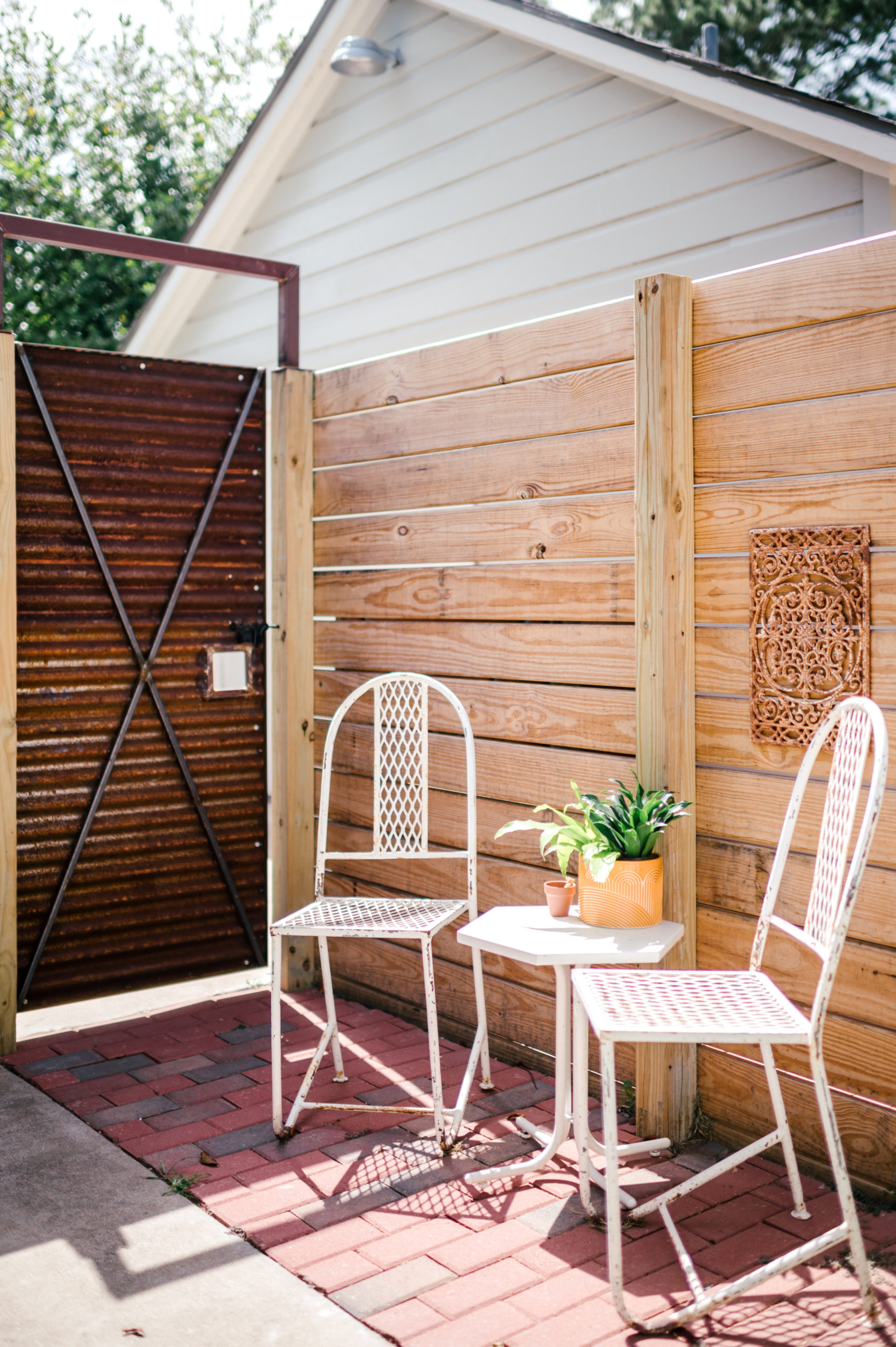 Metal patio chairs and table with a plant in the backyard