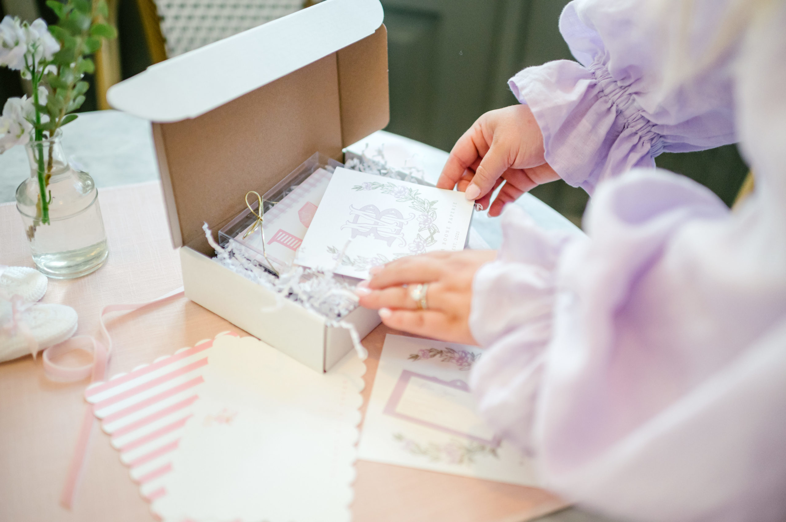 Woman hands boxing up a client paper invitation order for brand photoshoot