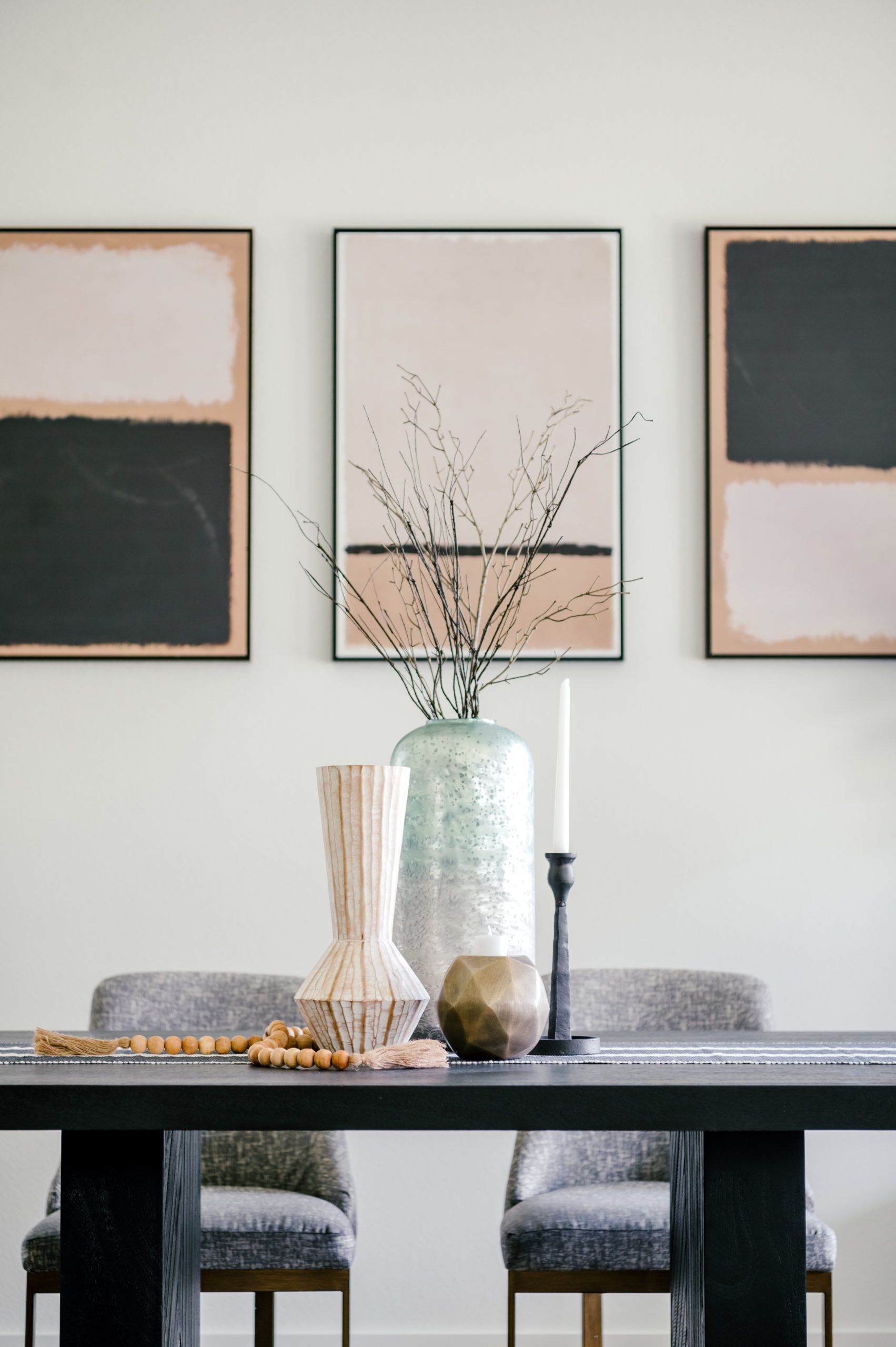 Professional interior photography of dining room with grey seats and a black wooden table with vases and a candle on top