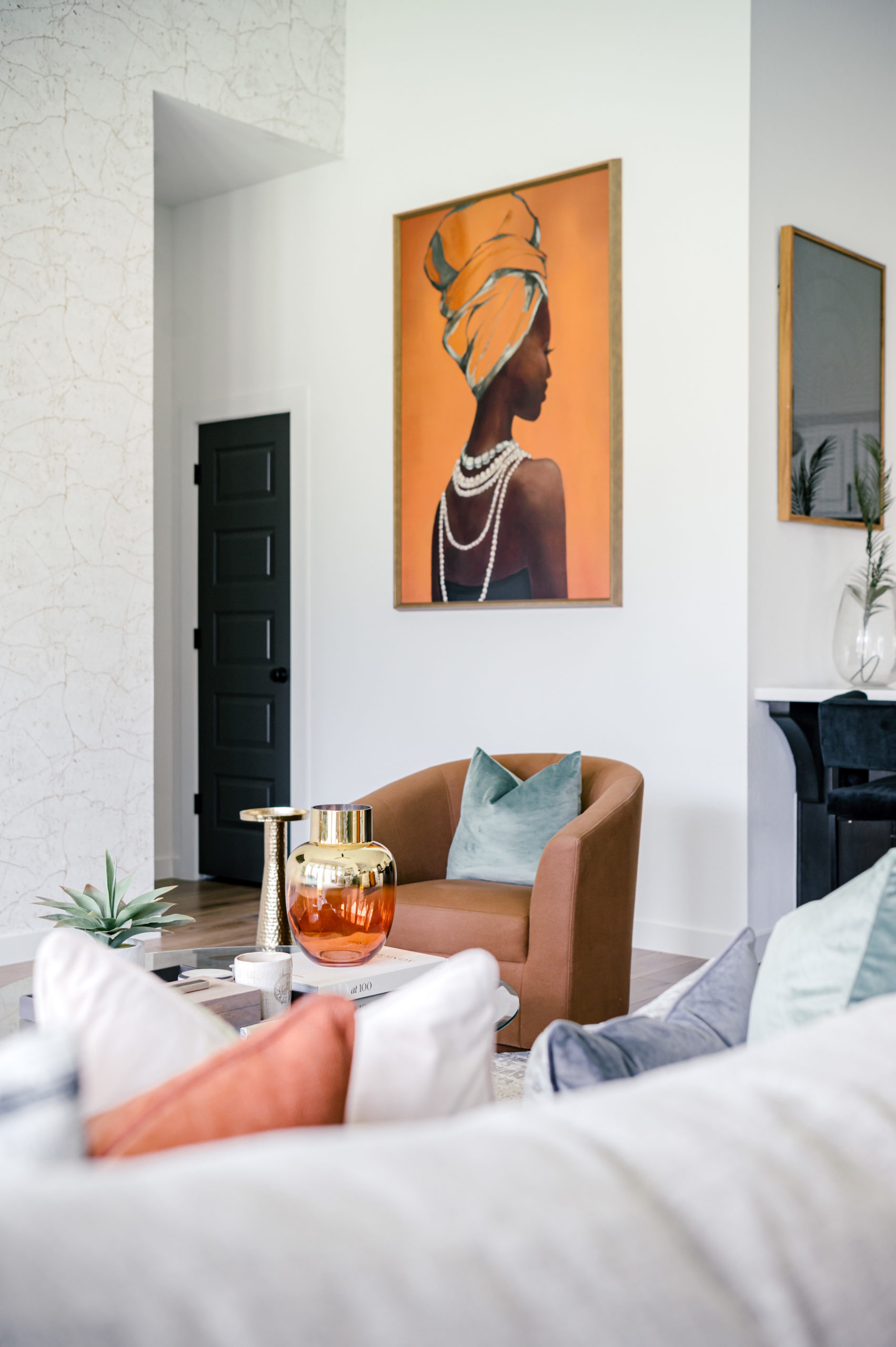 Brown leather love seat and green pillow in a living room that has an art piece of a woman on the wall taken by a houston interior photographer